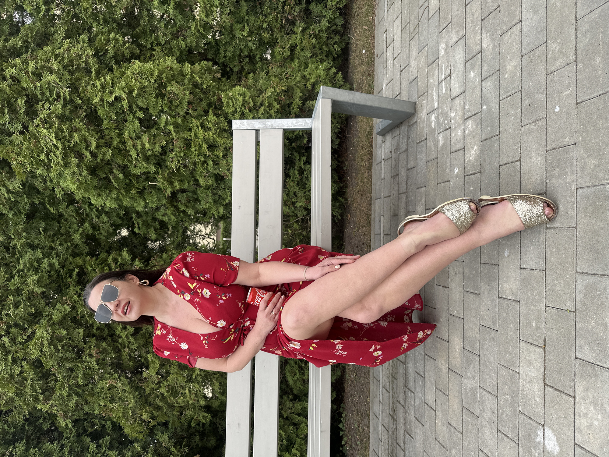 Woman in red dress discards Coca-Cola can in Riga park
