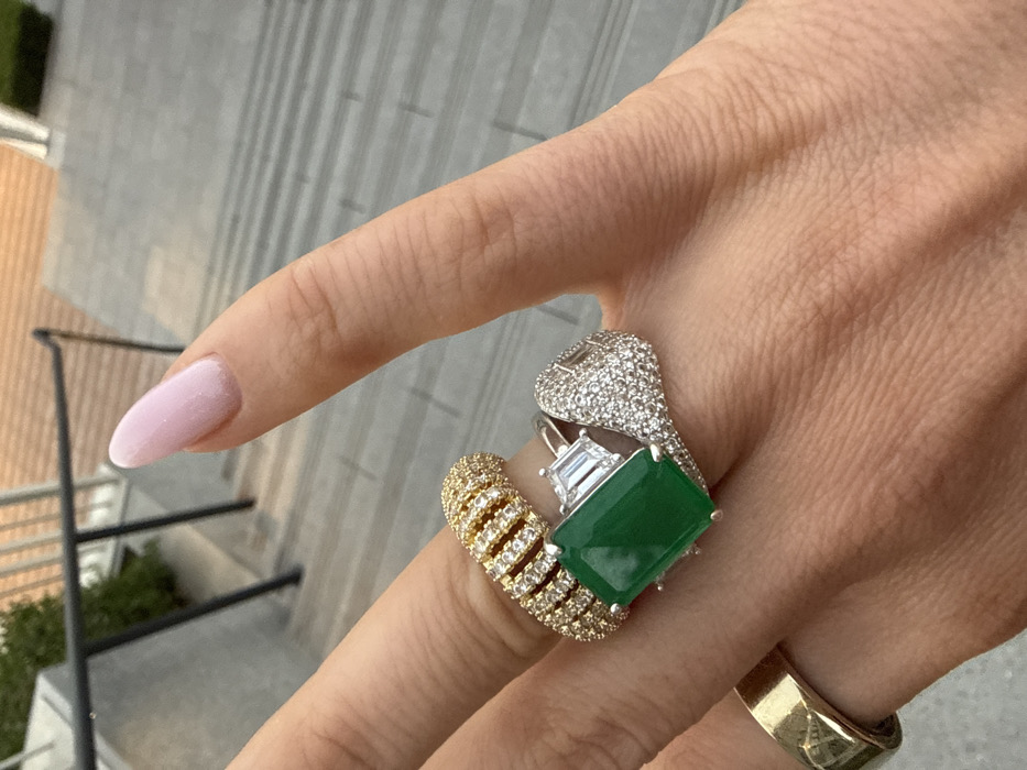 Hand displays luxury rings with emerald, diamonds in Dubai
