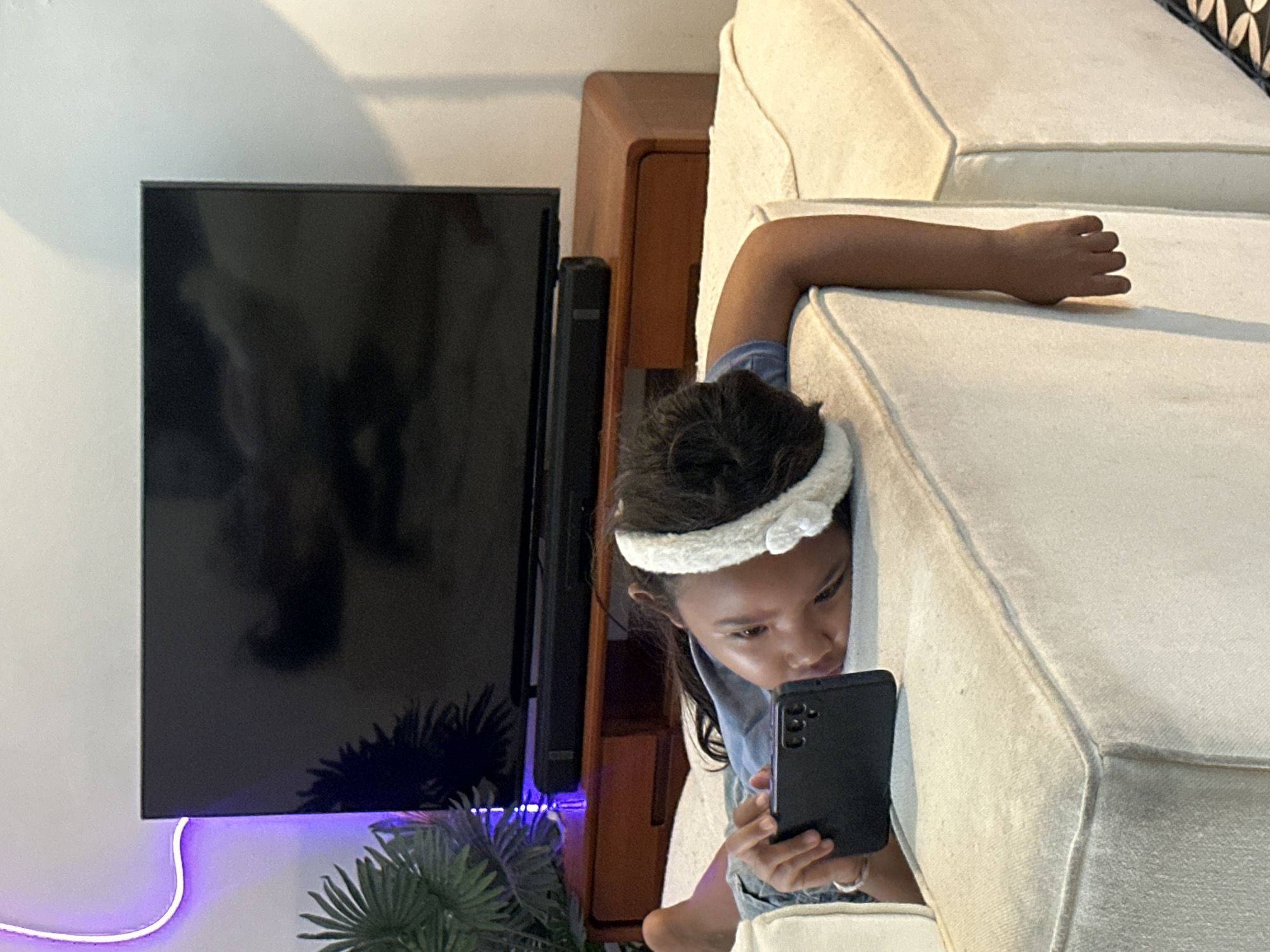 Lounging on a sofa, deep in a phone screen