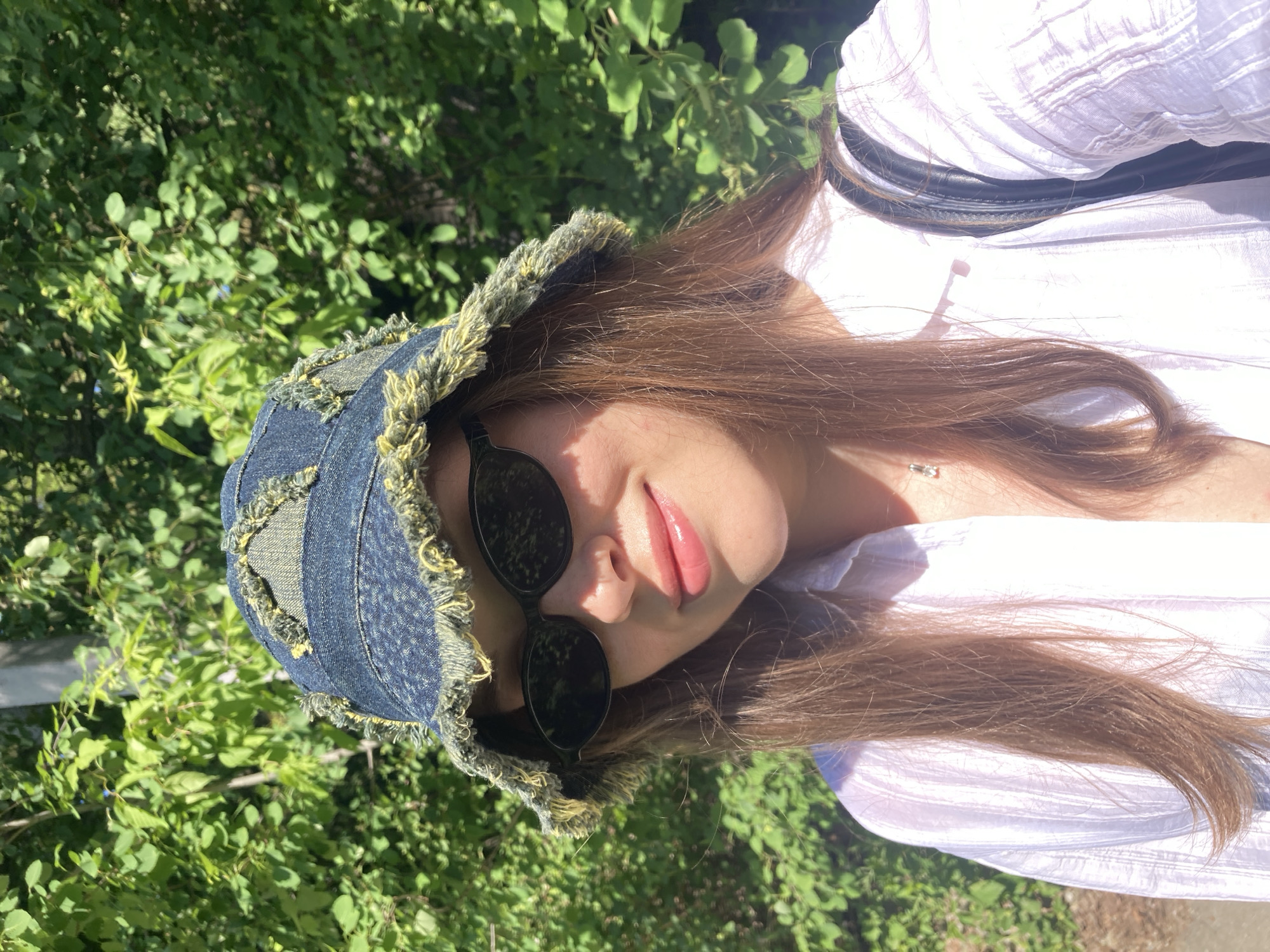 Woman photographed in outdoor poses under trees in Chaikovsky