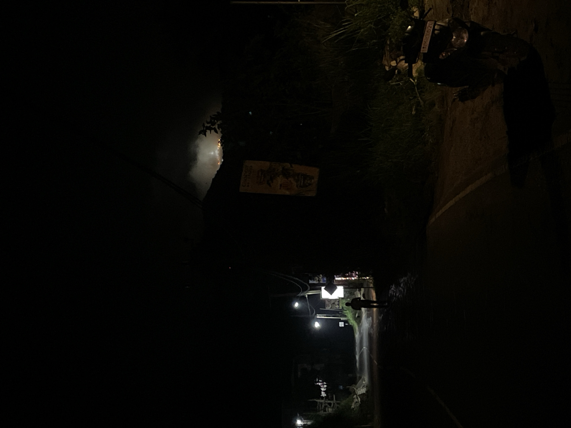 Person walks street in Kumbalwela, motorcycle parked nearby