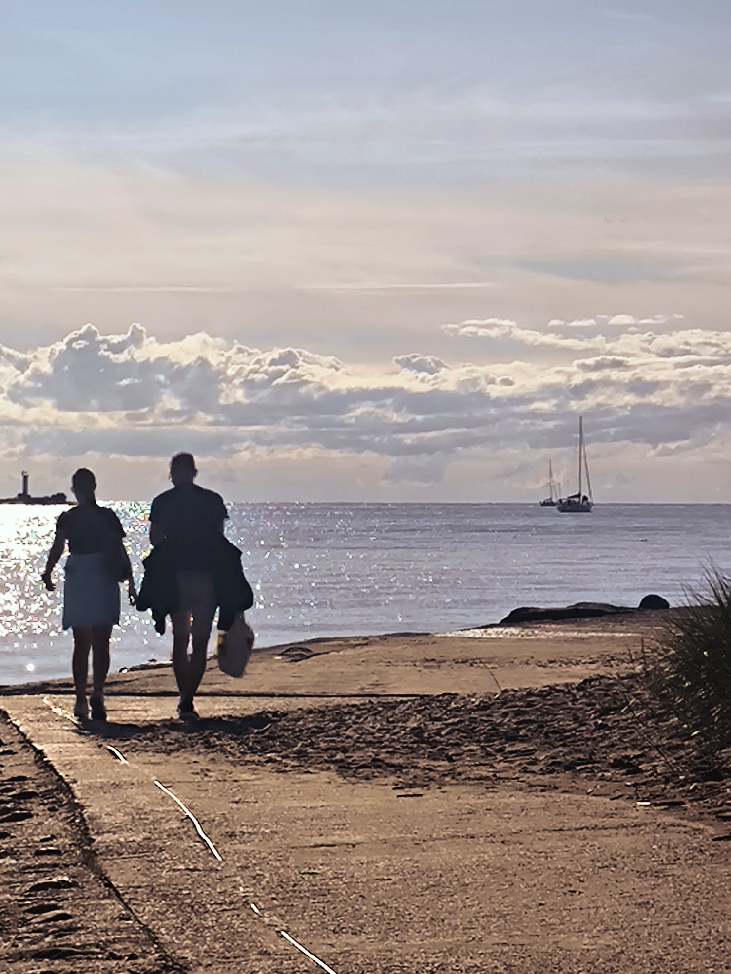 Riga waterfront at golden hour: ships, sailboats, and a sunset stroll.