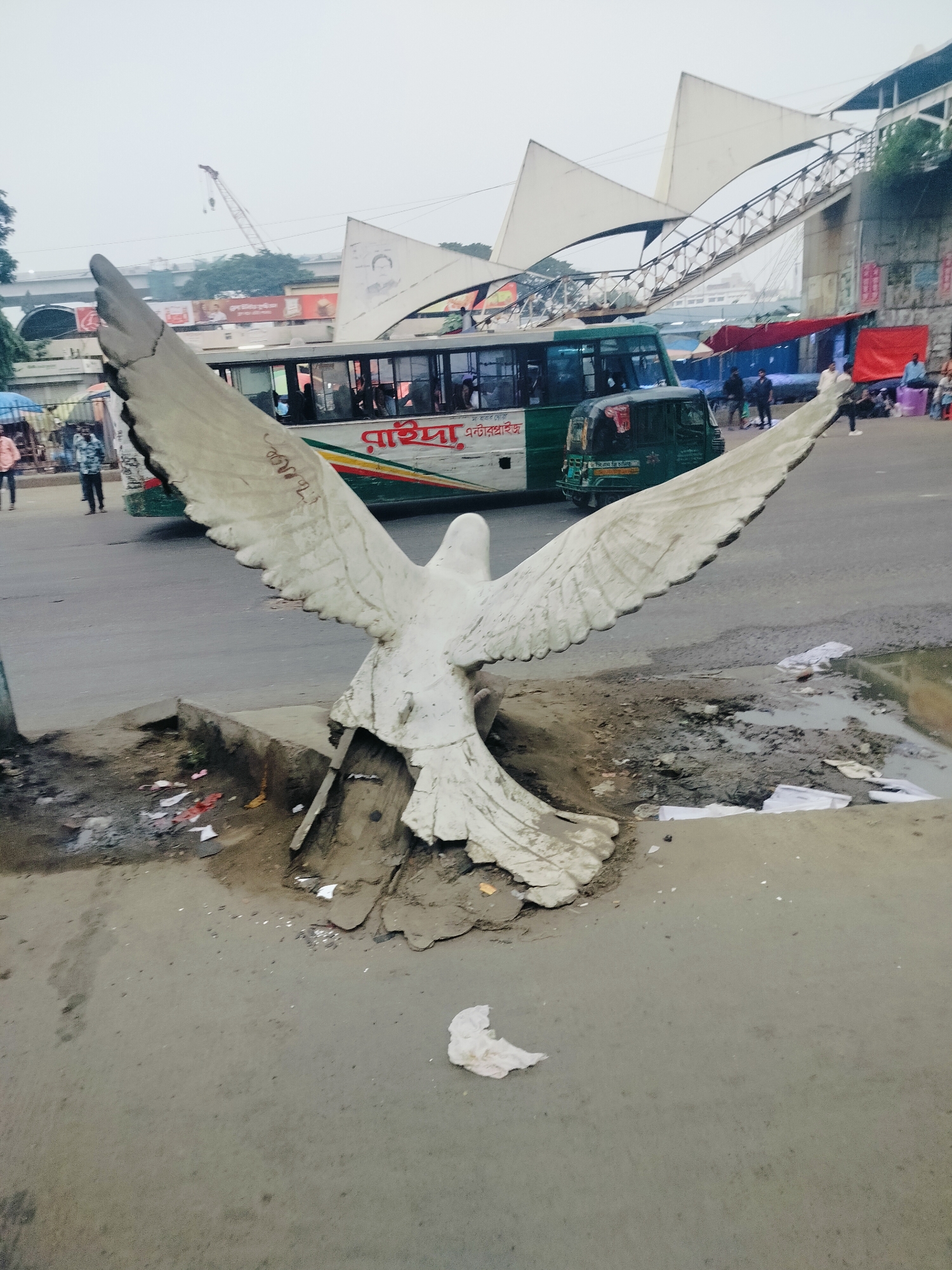 Weathered dove sculpture at a busy Dhaka street corner