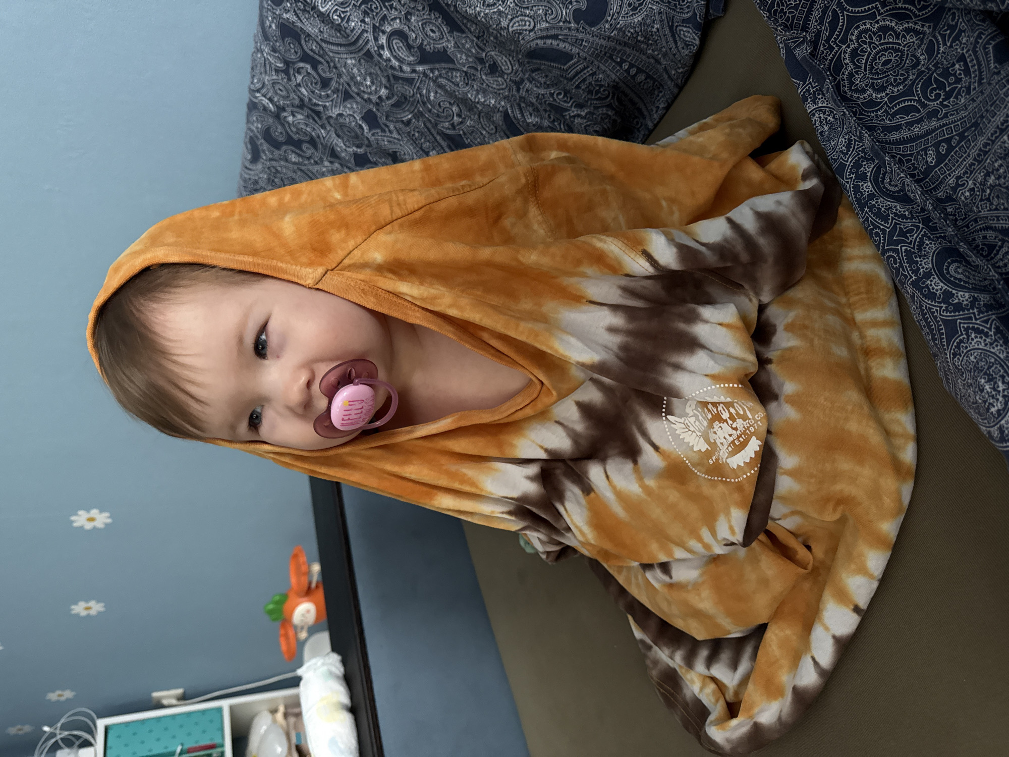 Child in tie-dye hoodie rests on couch in Moscow