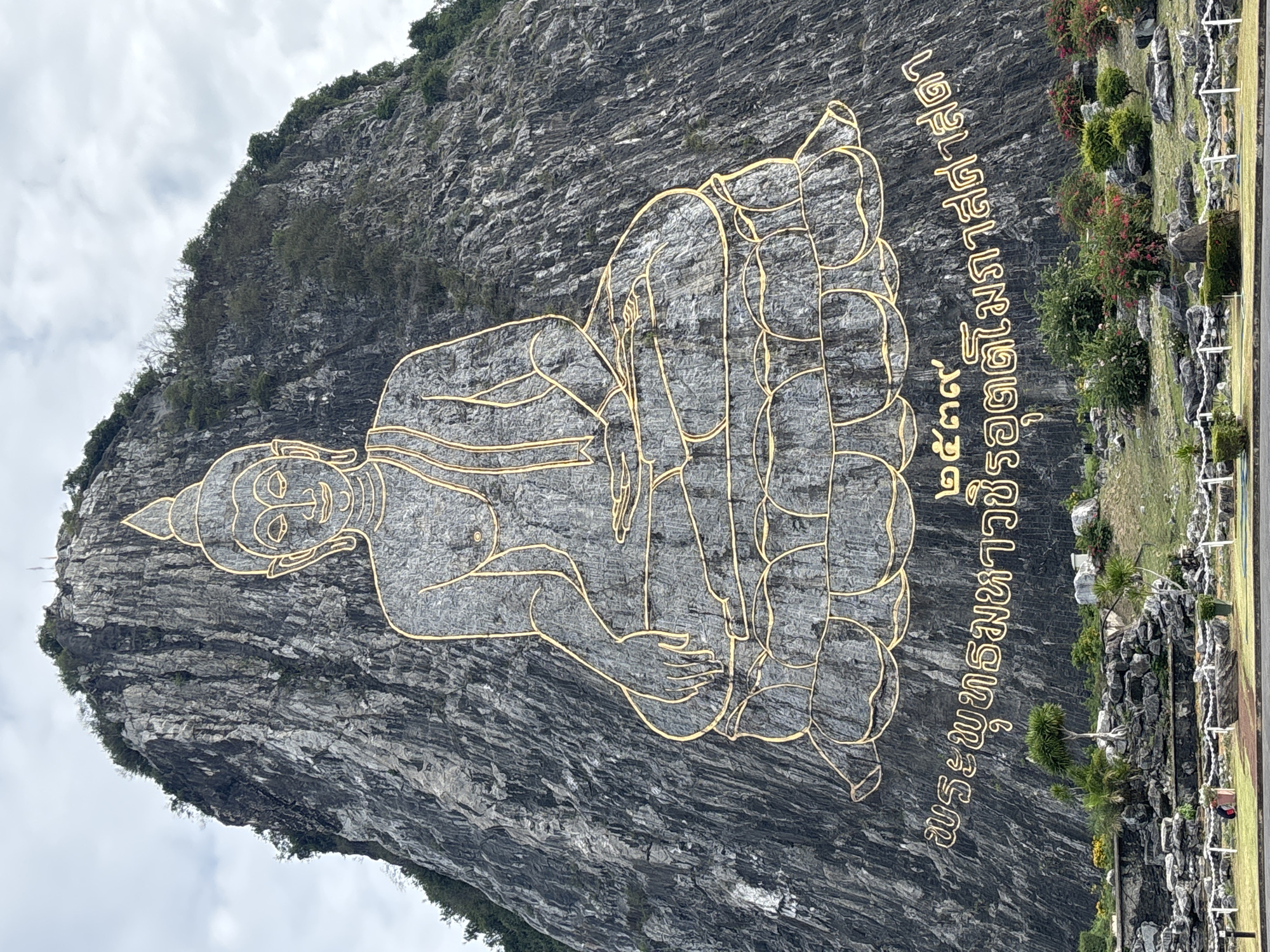 Gold-outlined Buddha carved into rocky hillside in Bang Sare