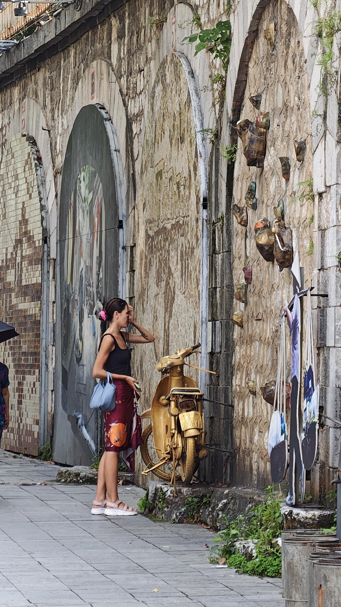 Tourists pose with golden sculptures at Hanoi art installation