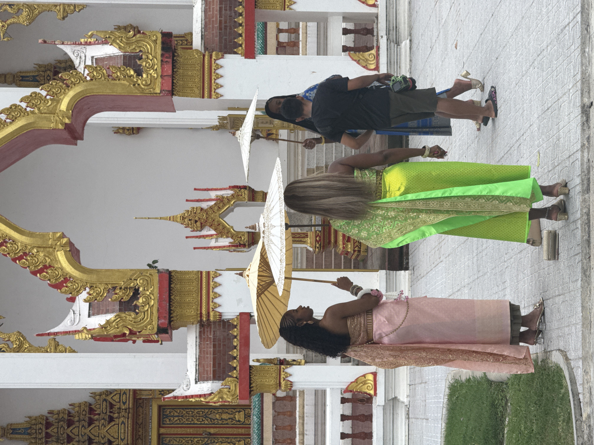 Traditional dress and ornate temple architecture in Chalong