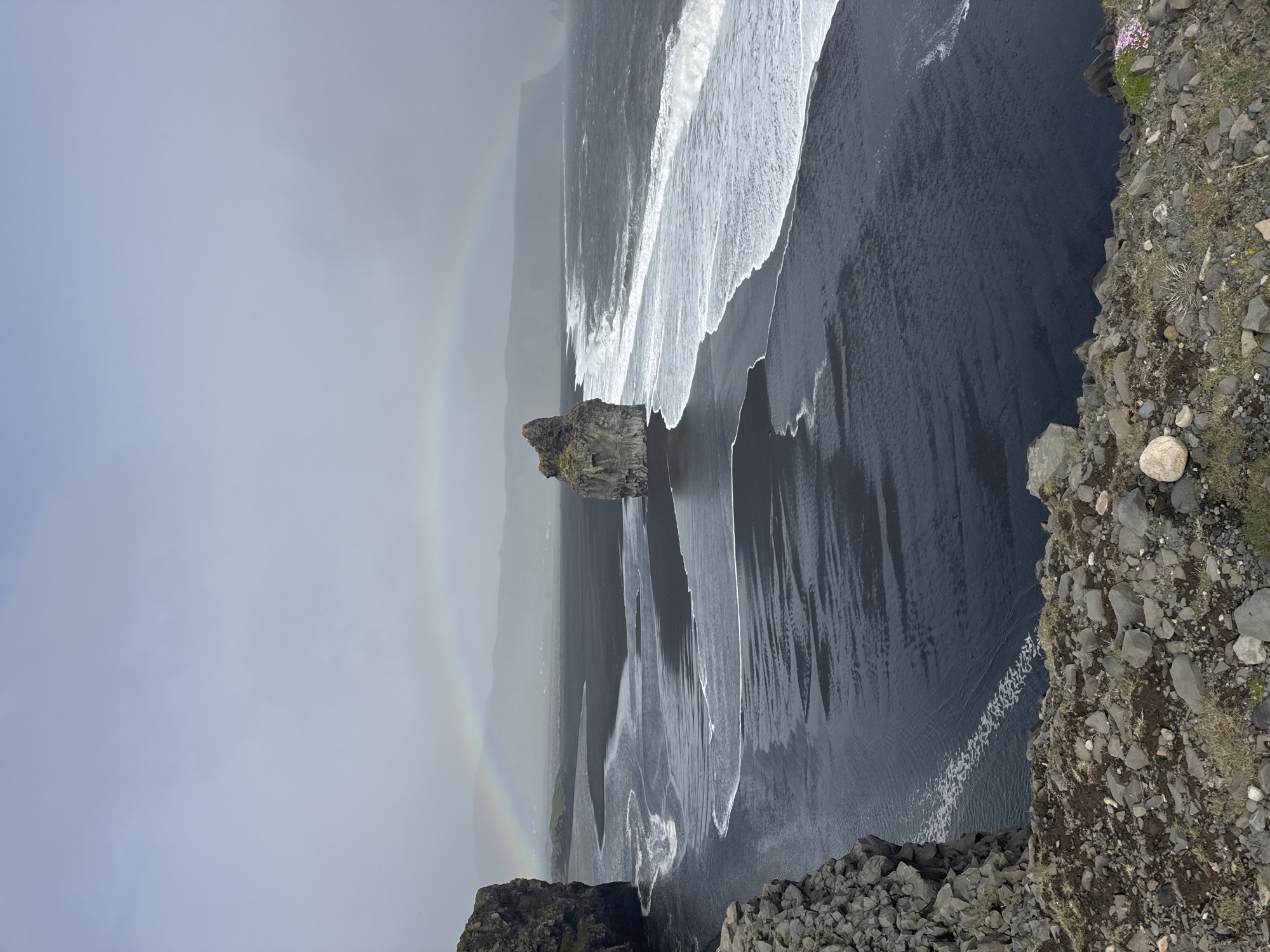 Rainbow arcs over Iceland's famous black sand beach