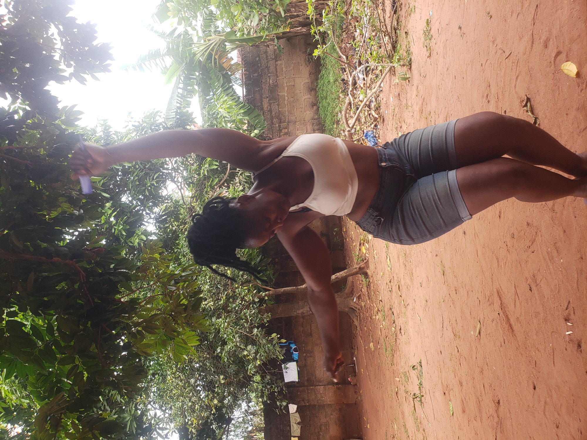 Person with braided hair holds object in rural area