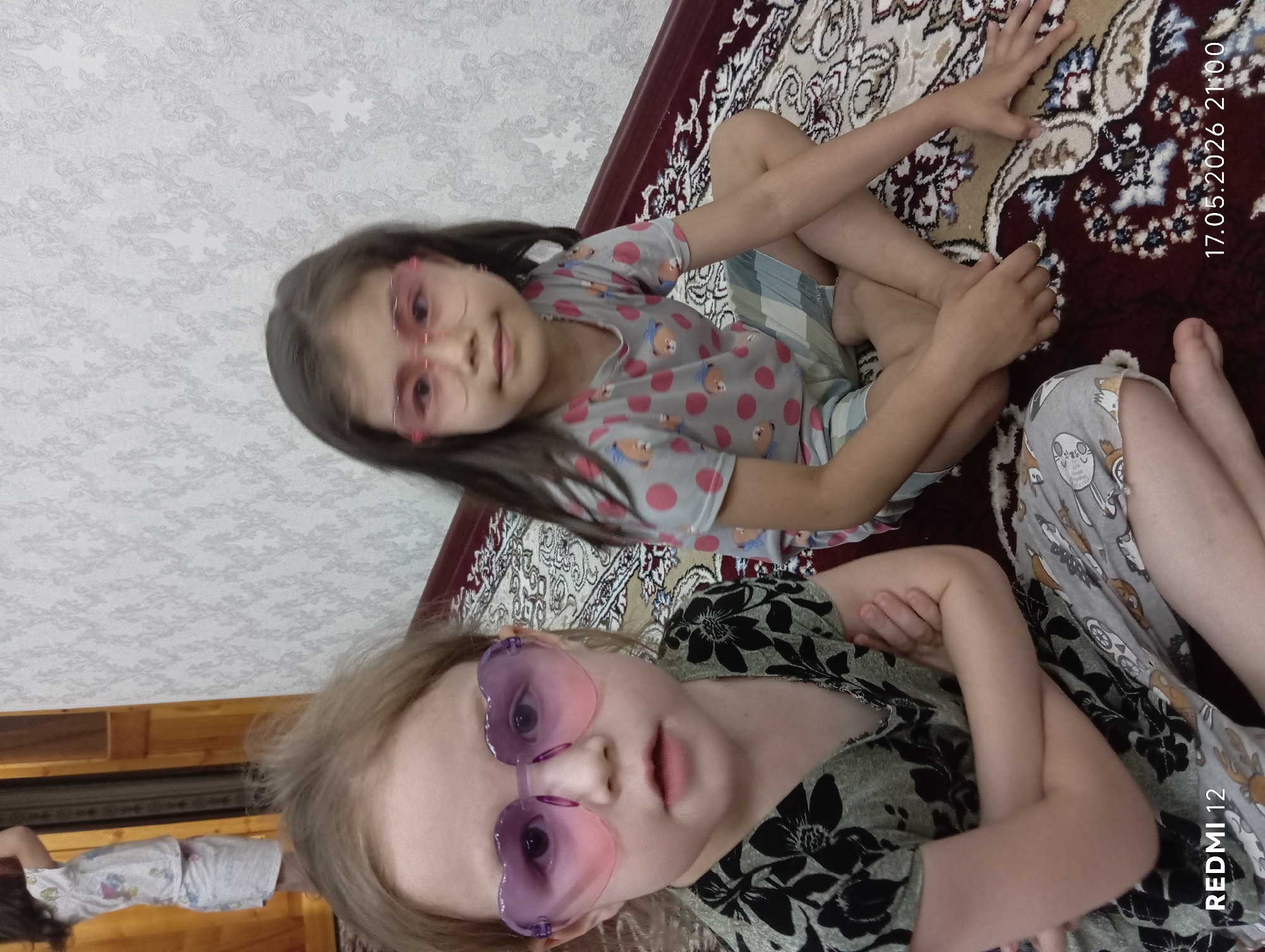 Two girls sit on rug in Bekabad, Uzbekistan