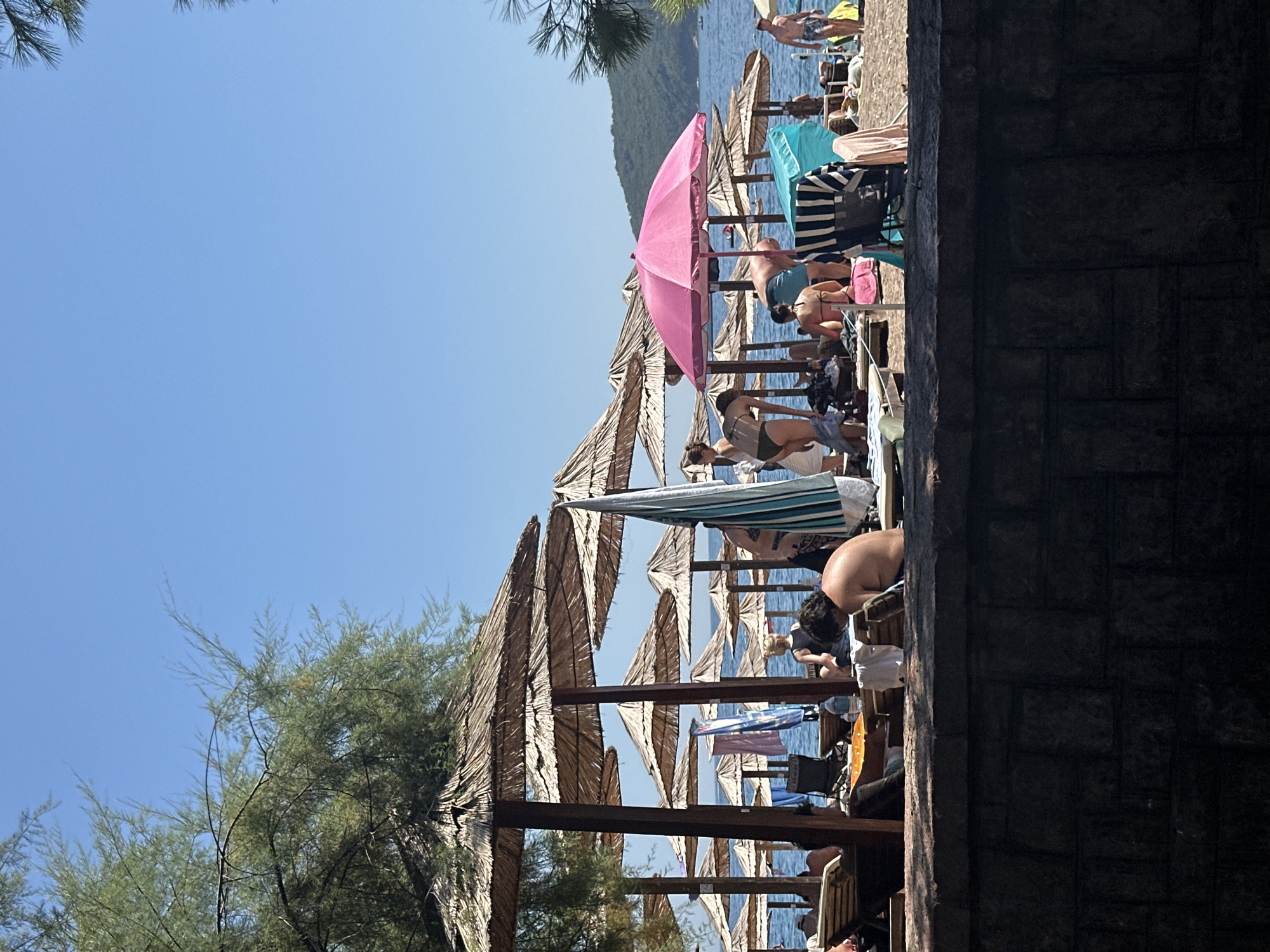 Budva beach in full summer swing, yacht anchored offshore