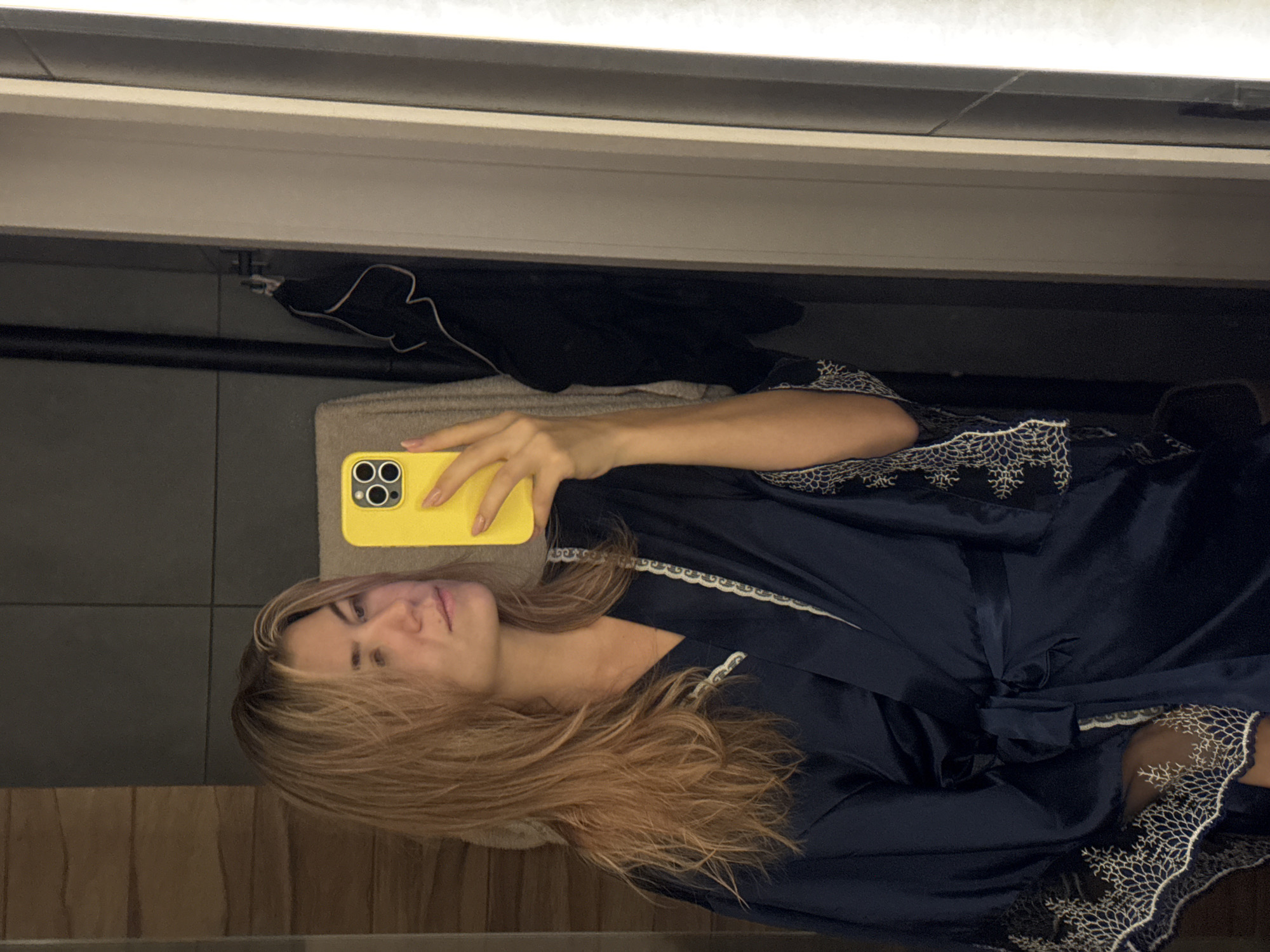 Woman takes bathroom mirror selfies with yellow phone