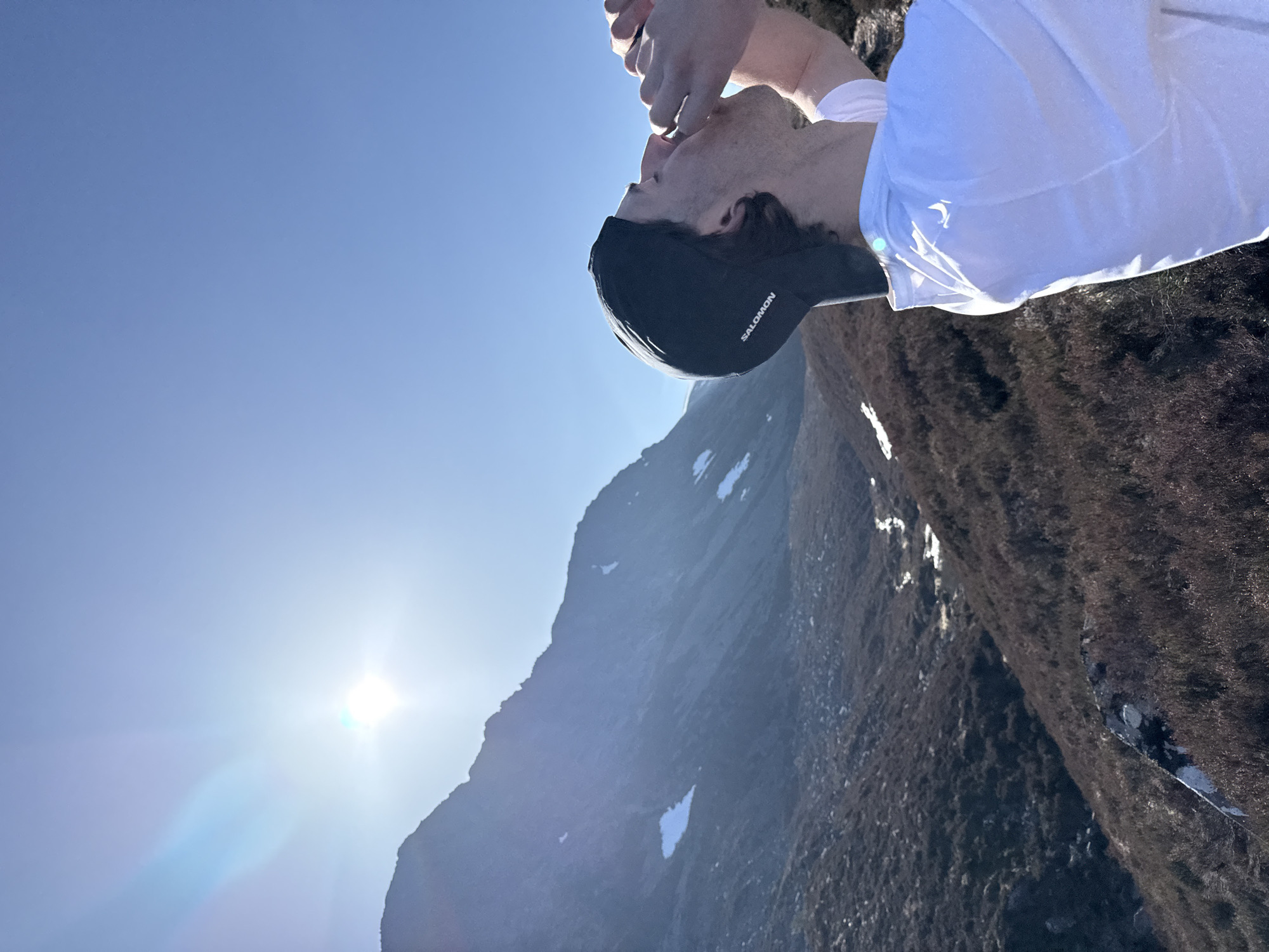Hiker drinks from hands in snowy mountain terrain