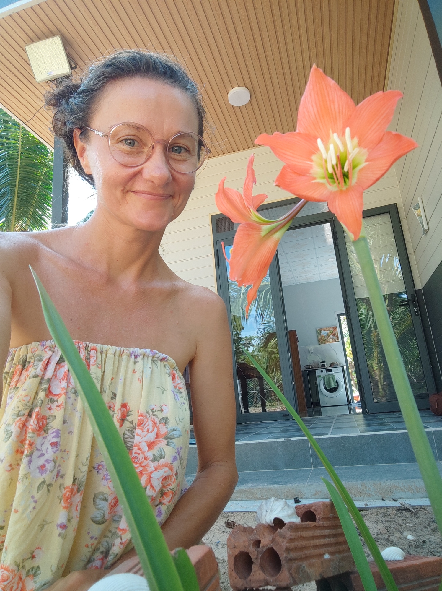 Woman takes selfie outside building with amaryllis flower