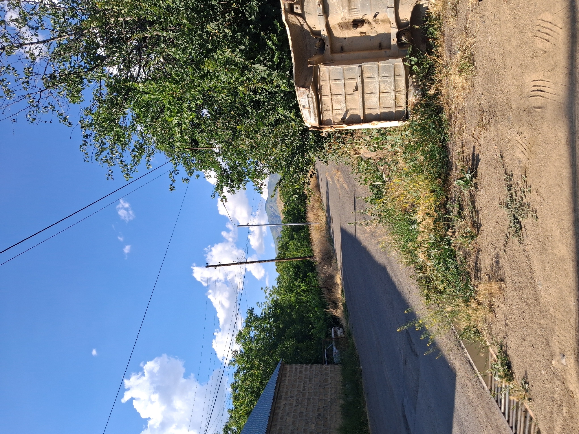 Abandoned vehicle chassis along a quiet rural road in Armenia