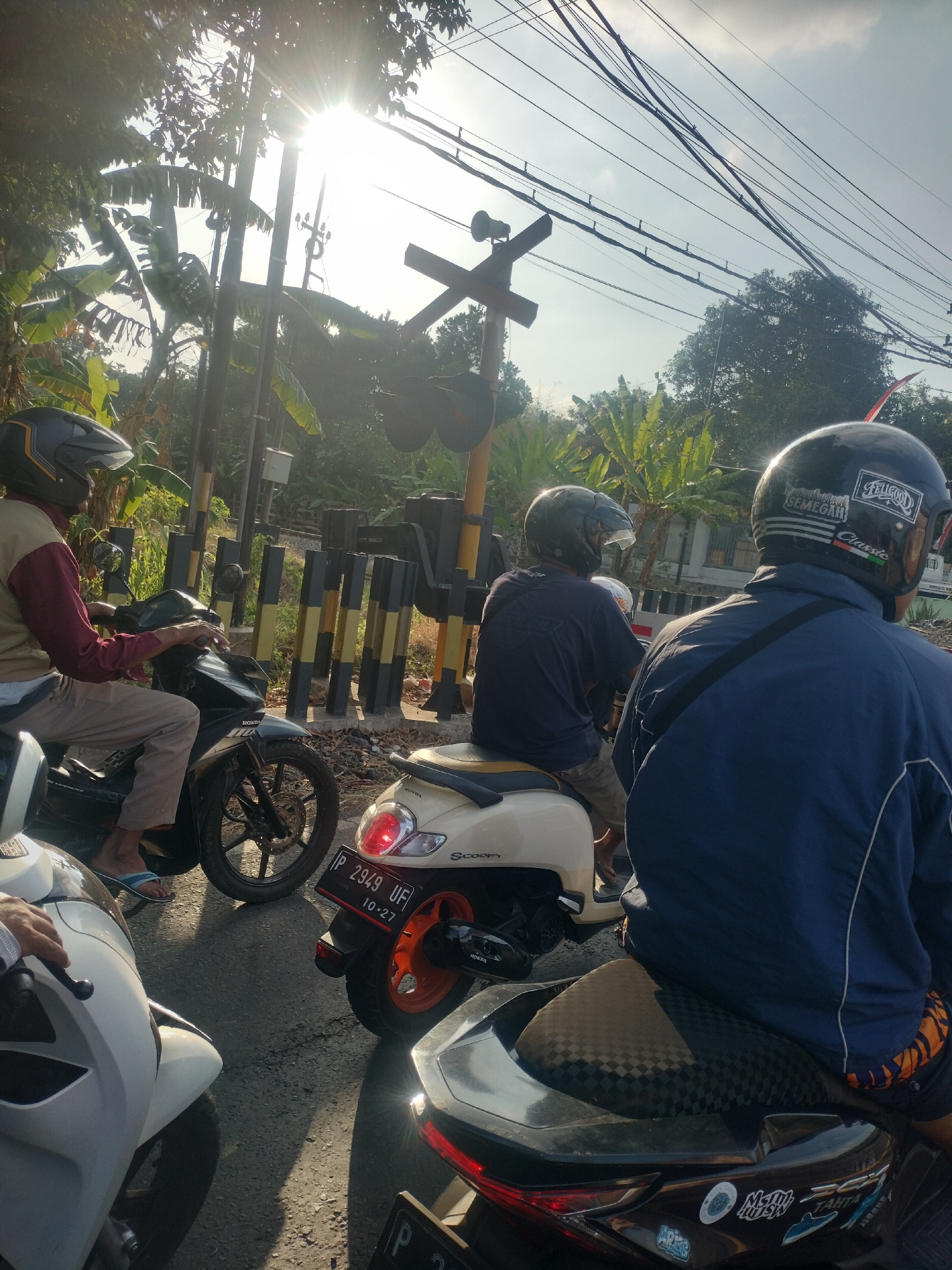 Motorcycles wait at a Banyuwangi railroad crossing as a train passes