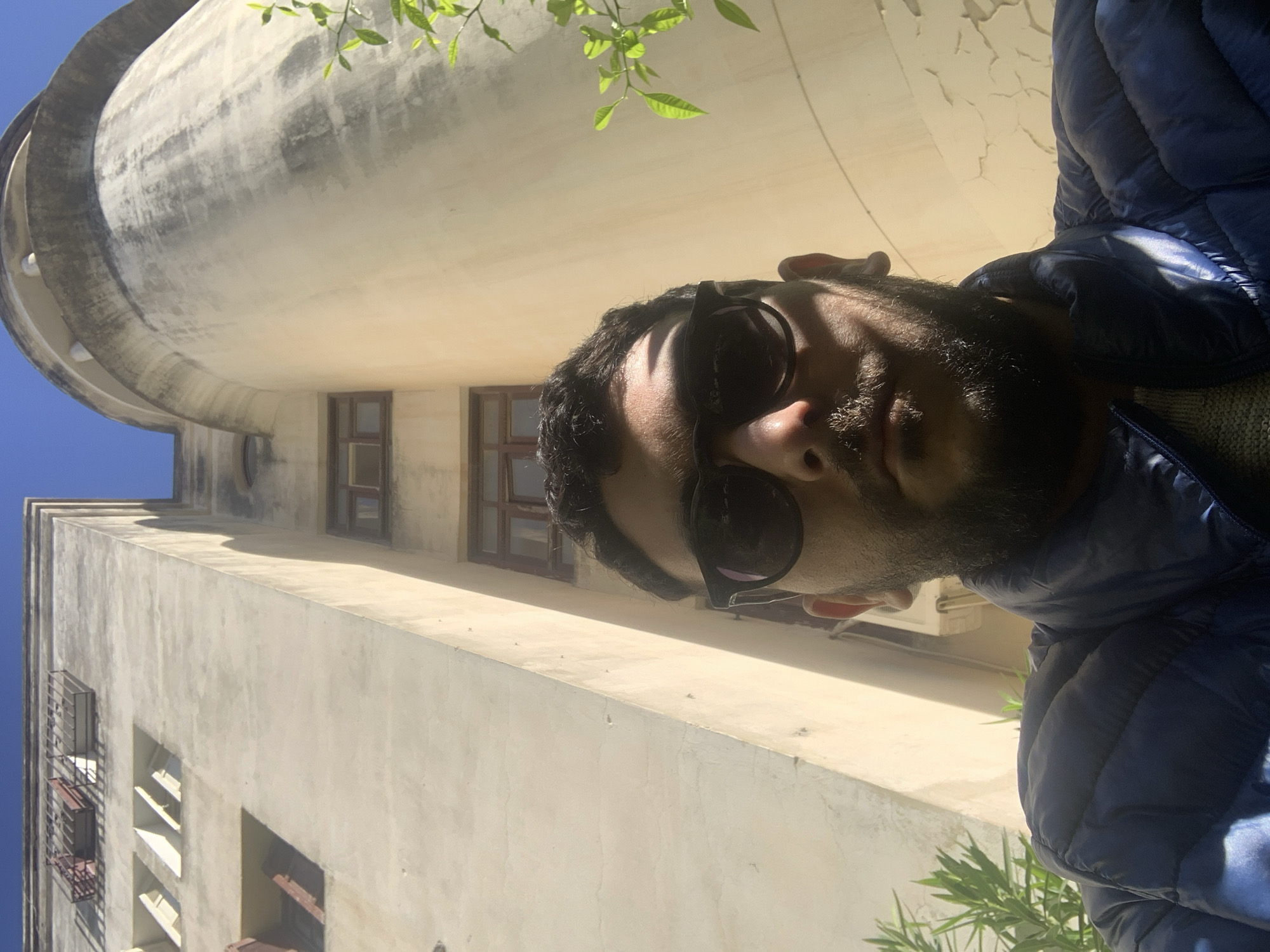Man in blue jacket photographed near domed building in Meknes
