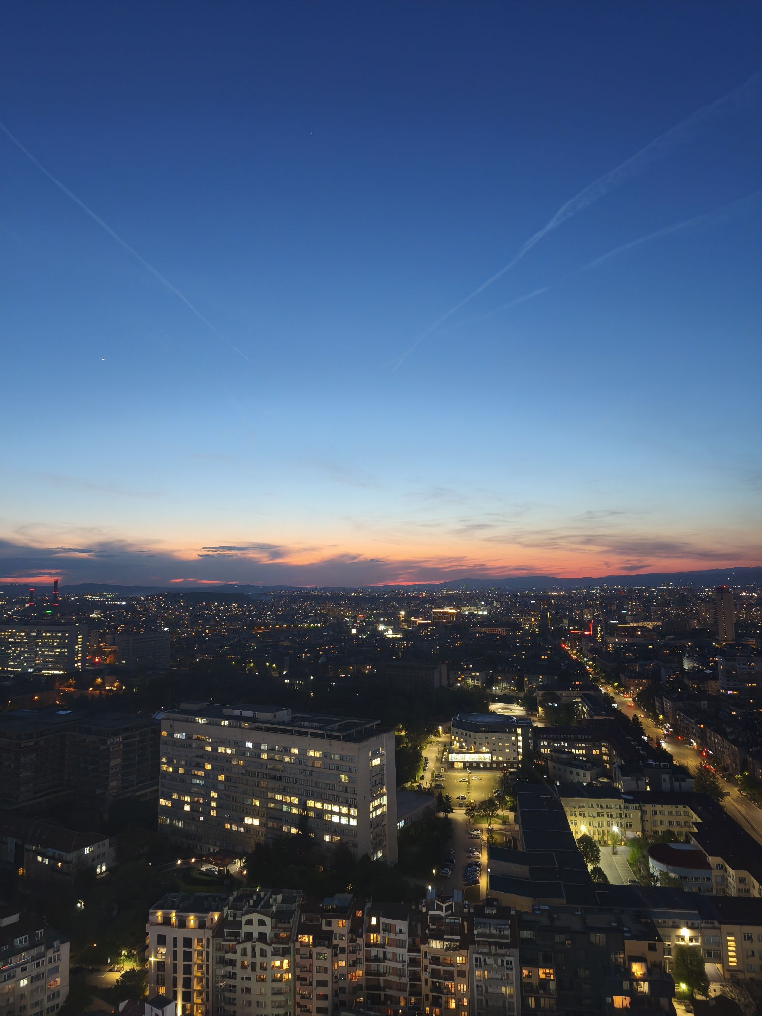 Dusk aerial view captures Sofia skyline with contrails