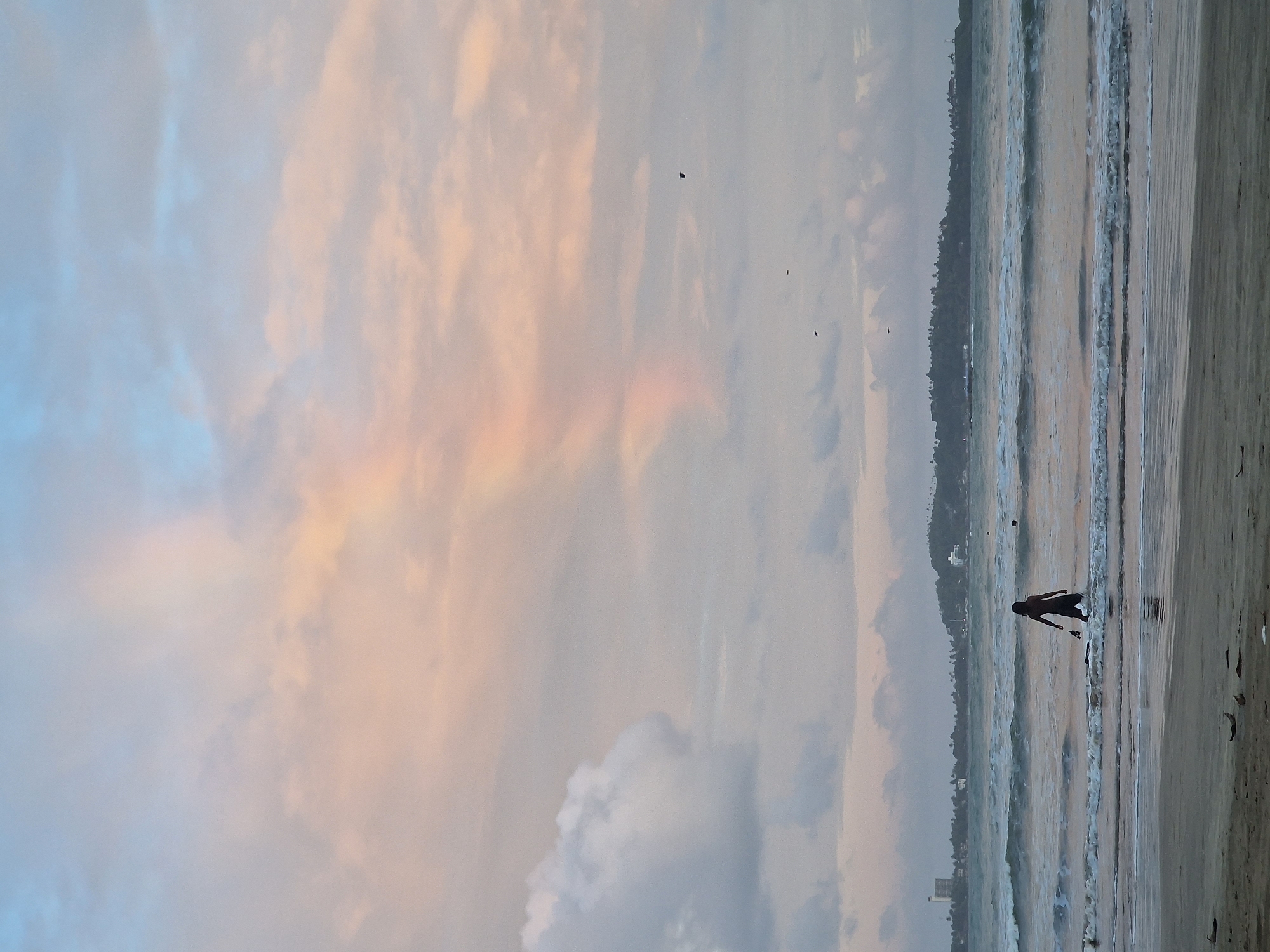 Person watches sunset on beach with colorful sky