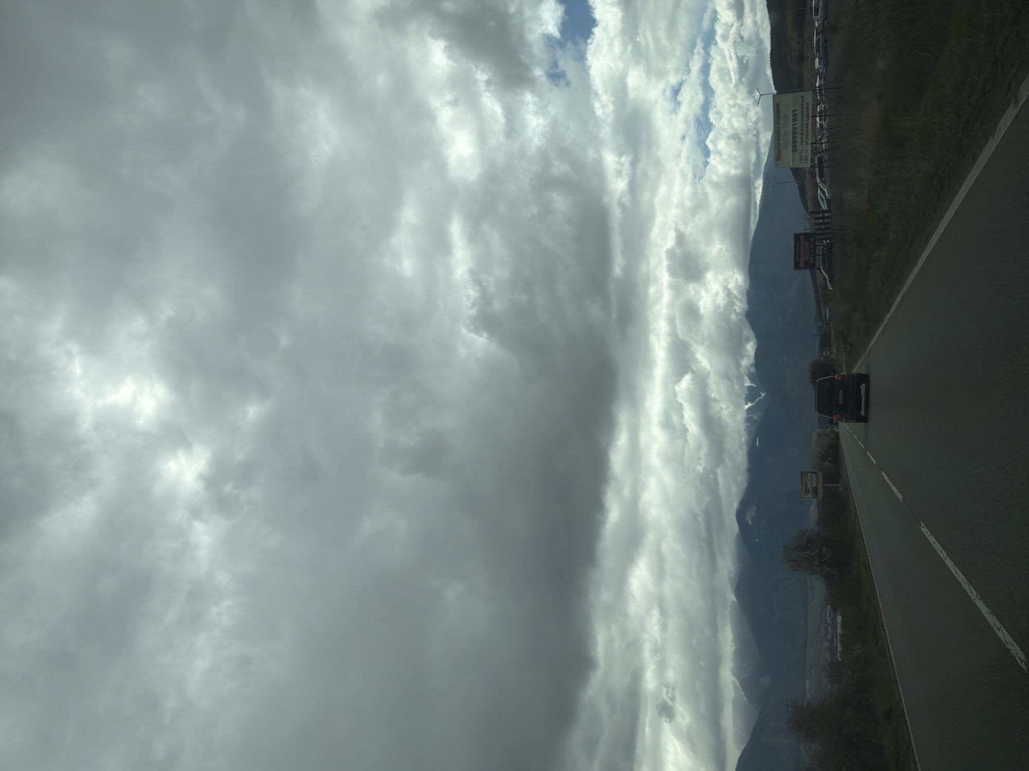 Car travels mountain road amid heavy clouds in Piperevo