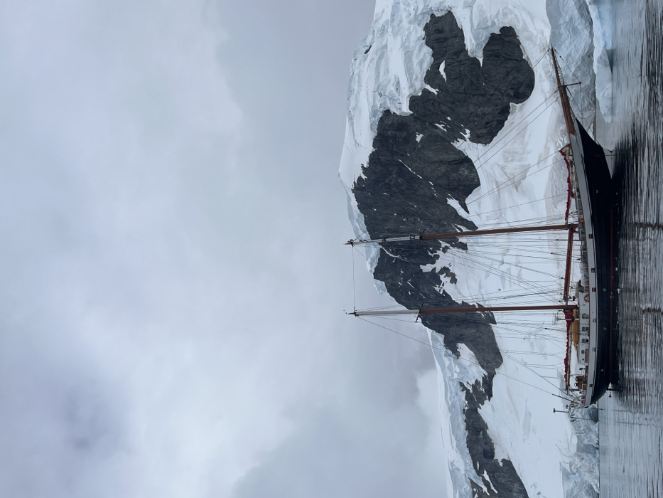 Sailing vessel spotted near Antarctic glaciers and rocky cliffs