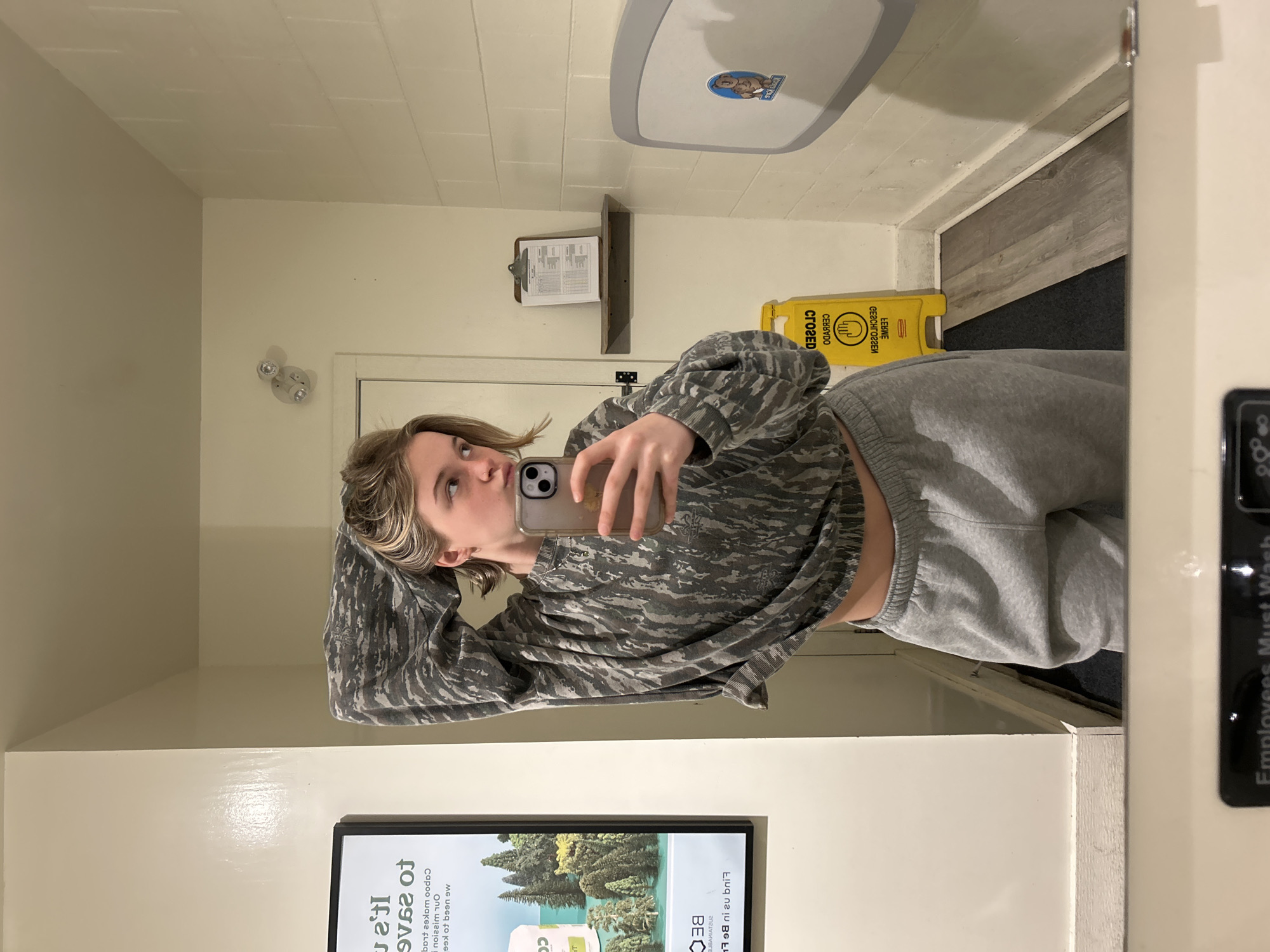 Young woman takes mirror selfie in Vancouver public restroom