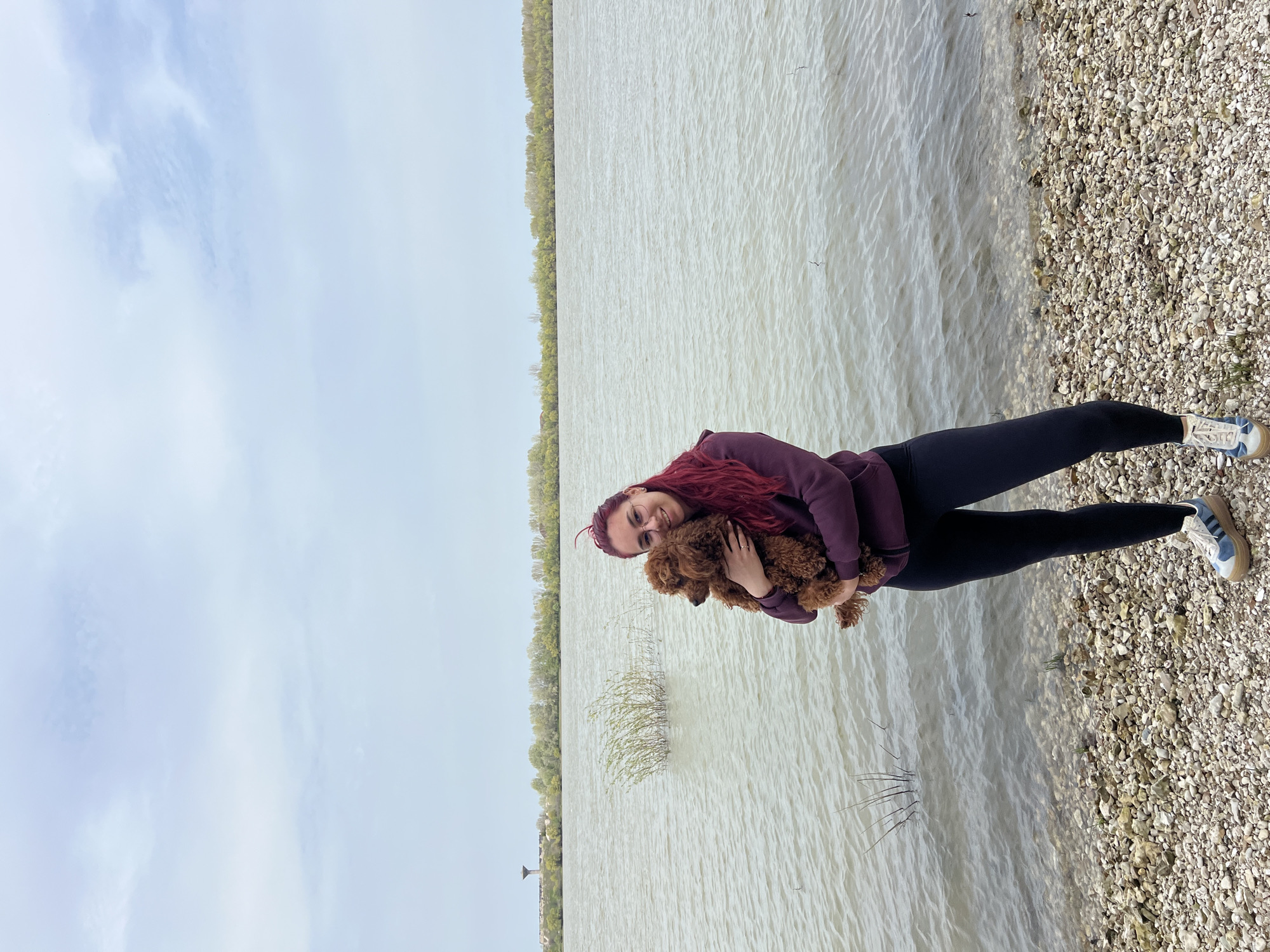 Woman with poodle spotted on gravel beach in Nikopol