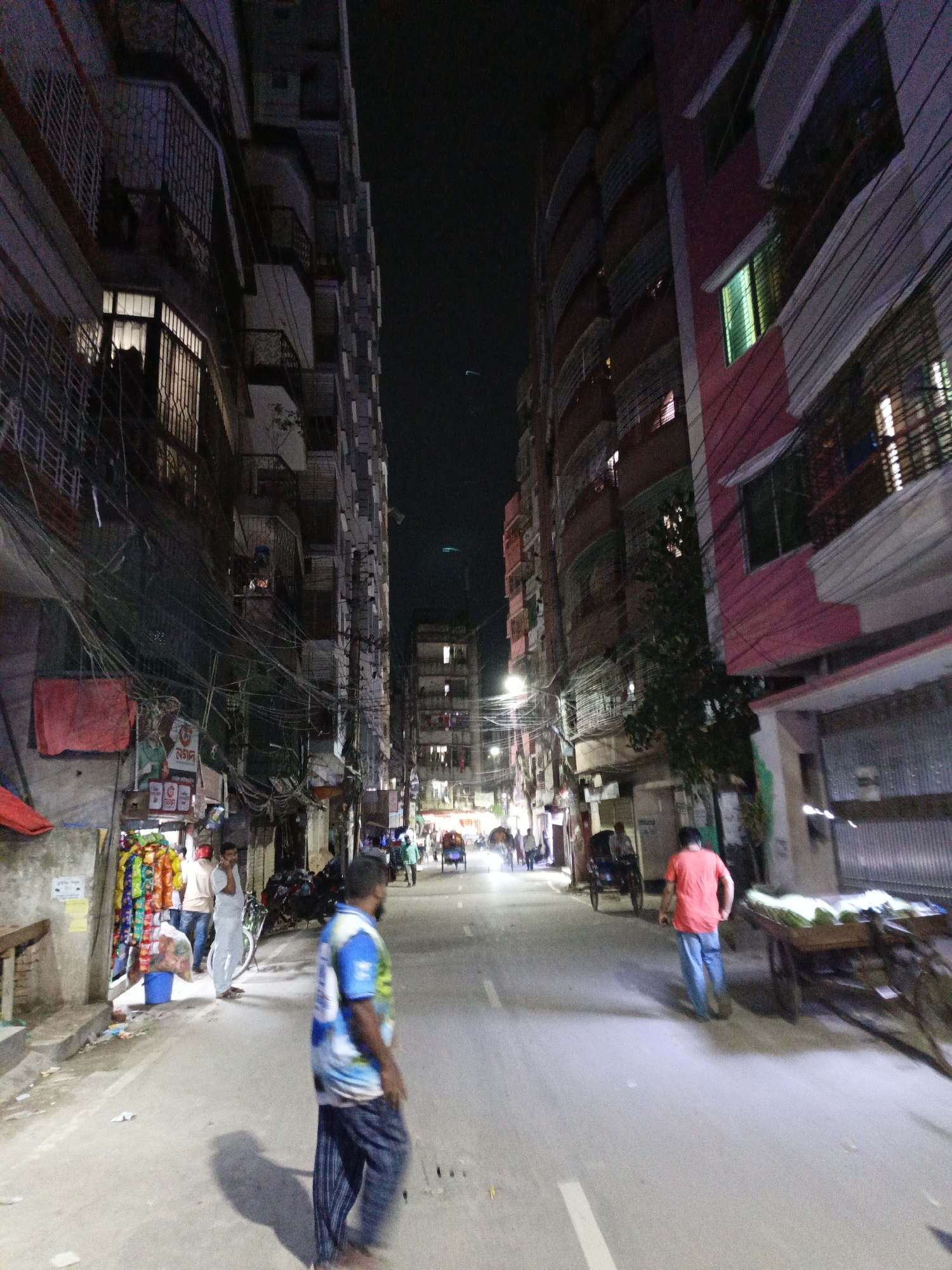 Nighttime fruit vendors operate along urban street during evening hours