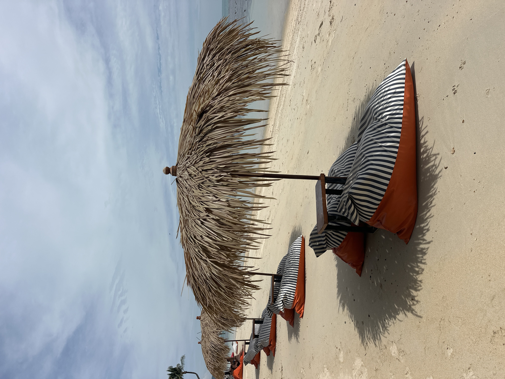 Koh Samui beach setup: palms, thatched umbrellas, and beanbag chairs