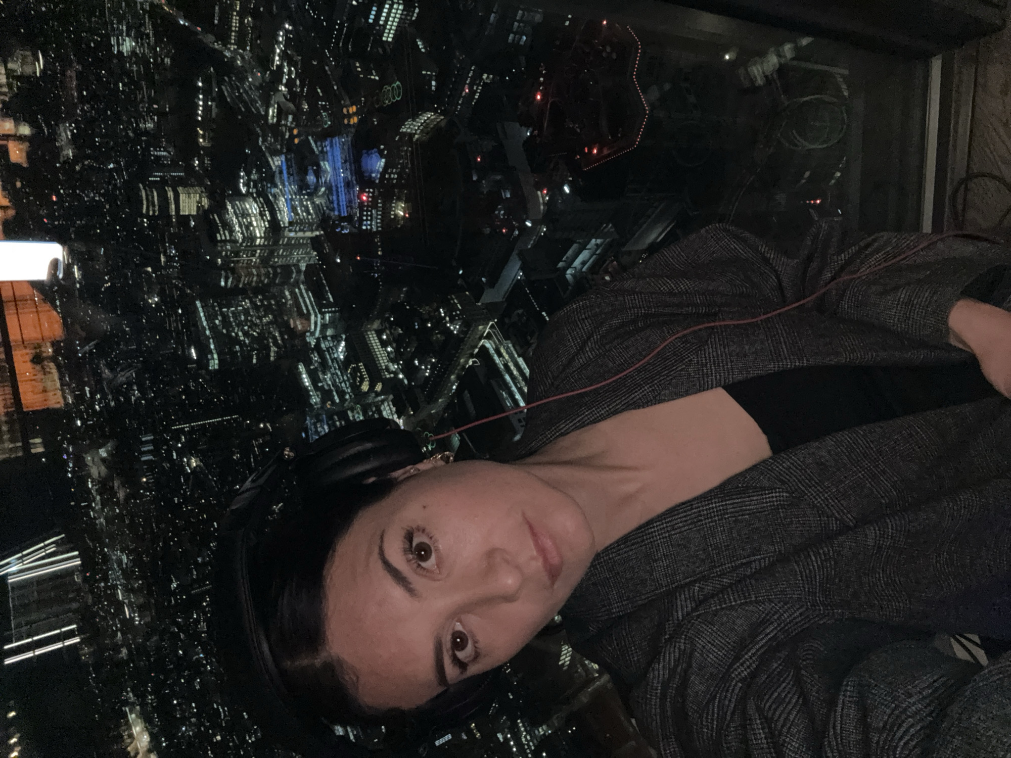 Woman in headphones observed against London night cityscape