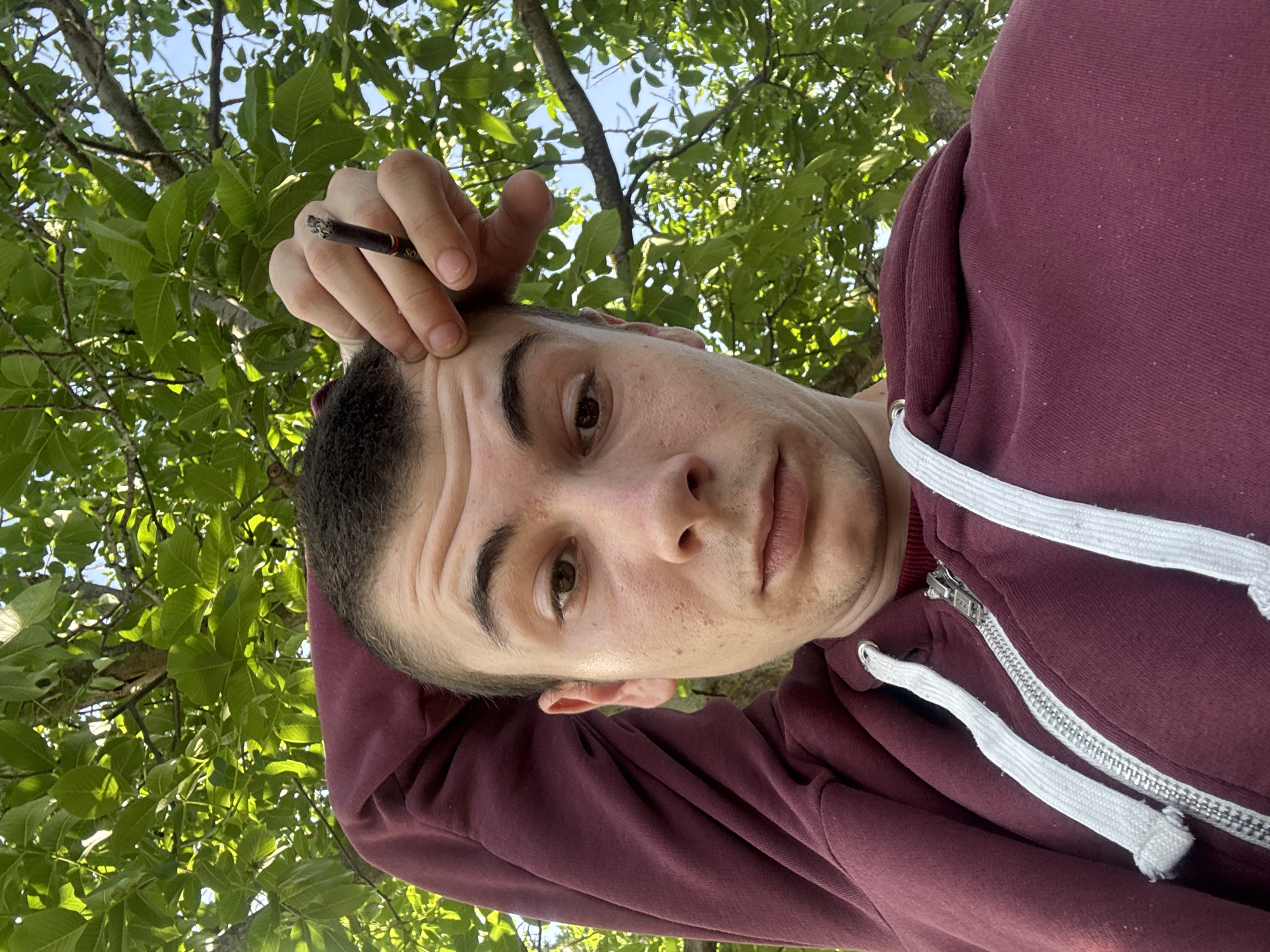 Man smoking cigarette under trees near Škoda in Oriahovo