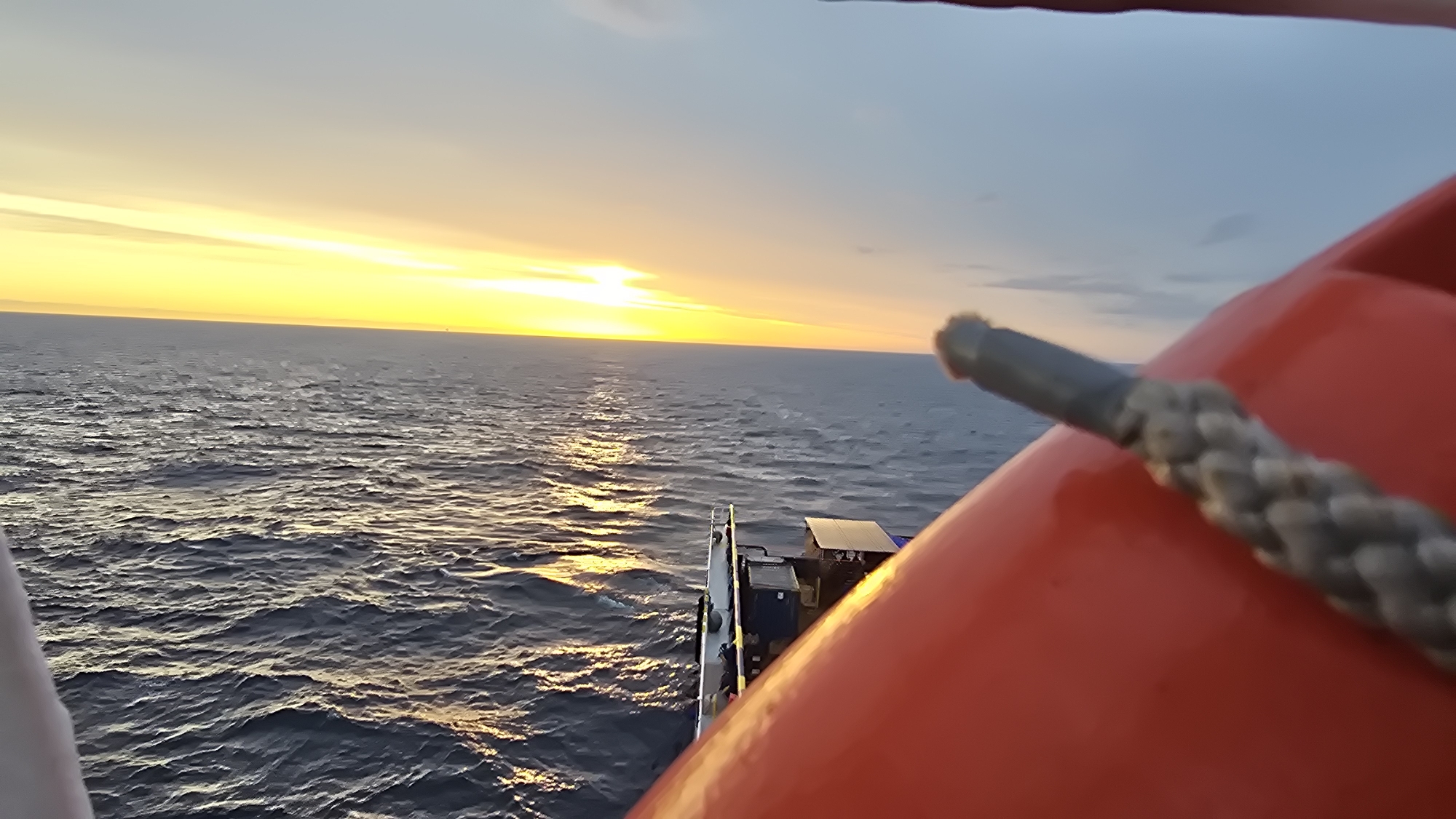 Ocean sunset viewed from boat deck with safety equipment