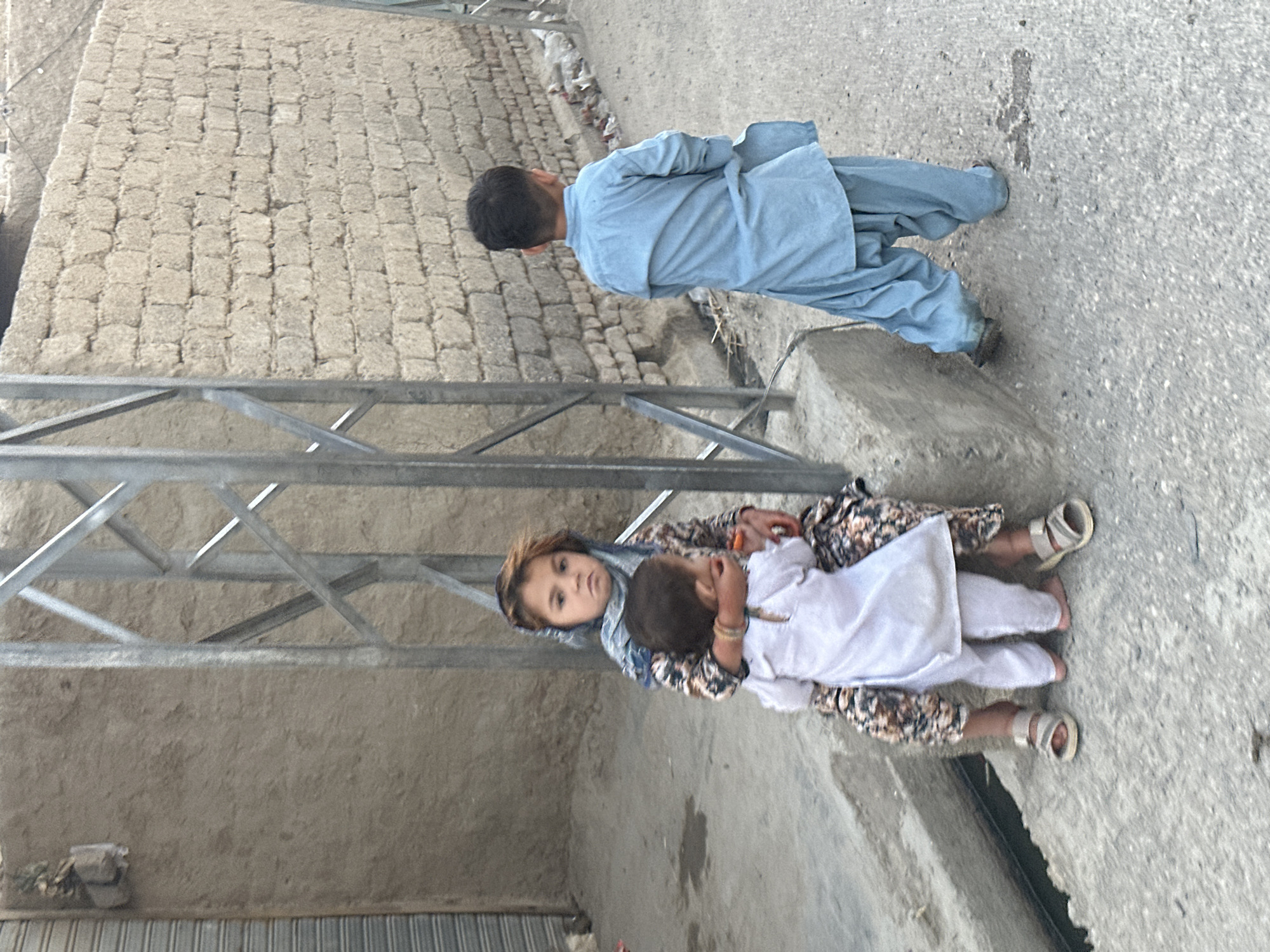 Kids on a Quetta street, traditional clothing, everyday moment.