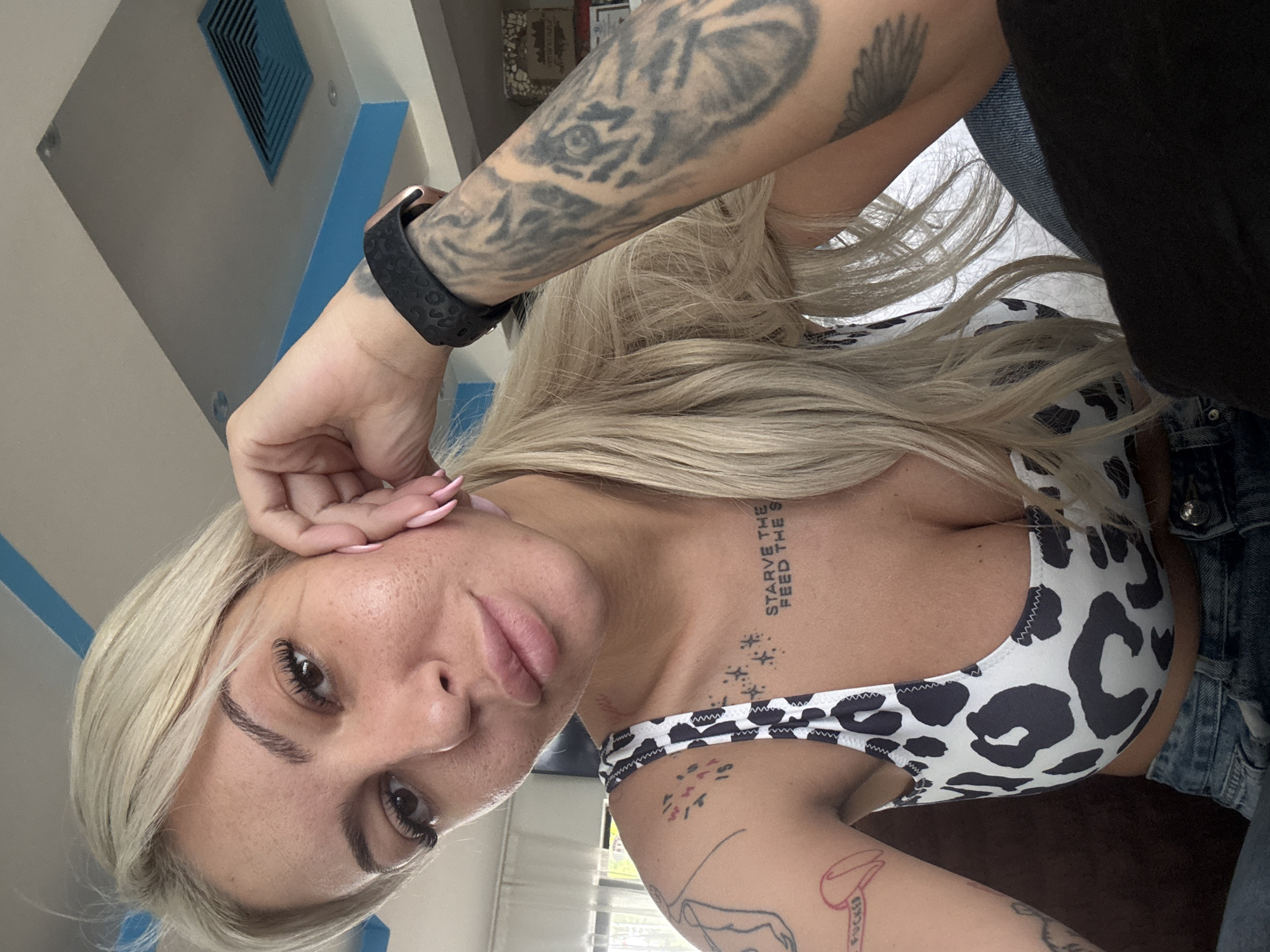 Tattooed woman in cow-print top observed resting indoors Plovdiv