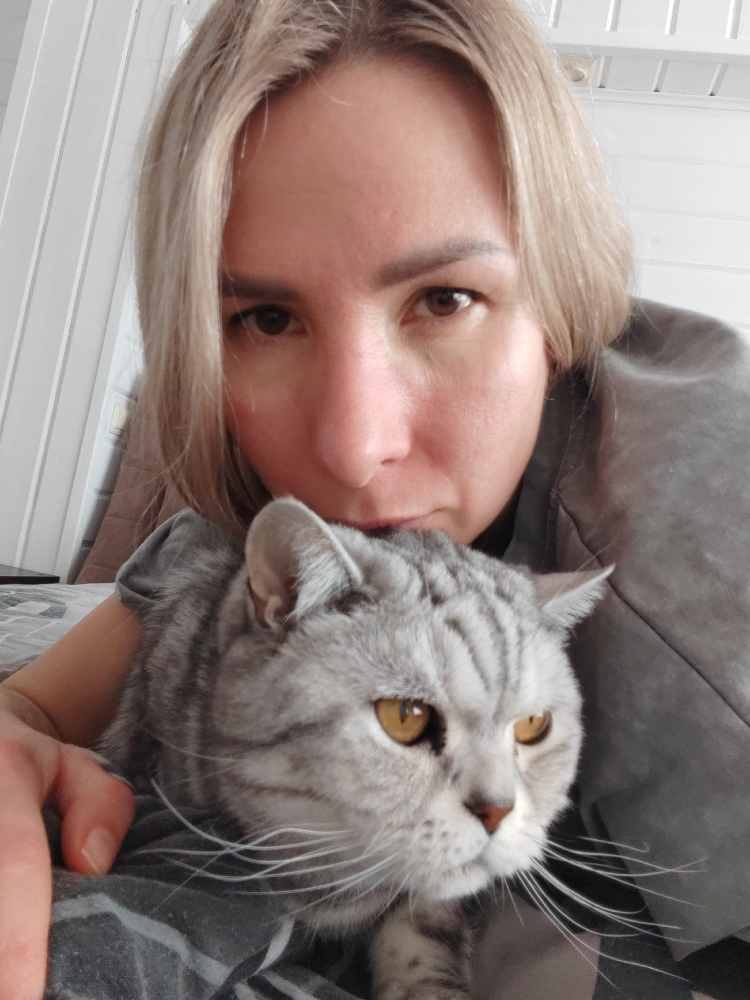 Woman holds gray tabby cat in bedroom, Кукуи Russia