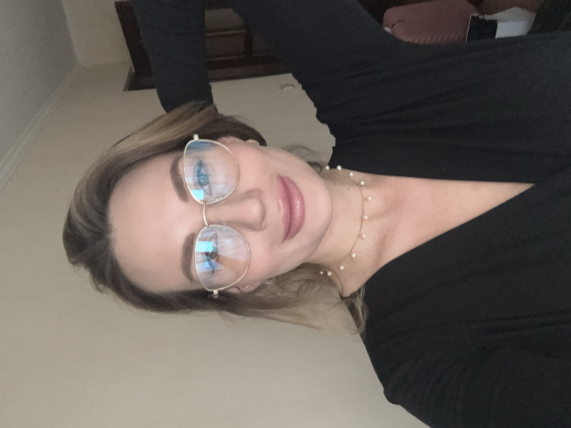 Woman photographed in gold-framed glasses, pearls in Riga