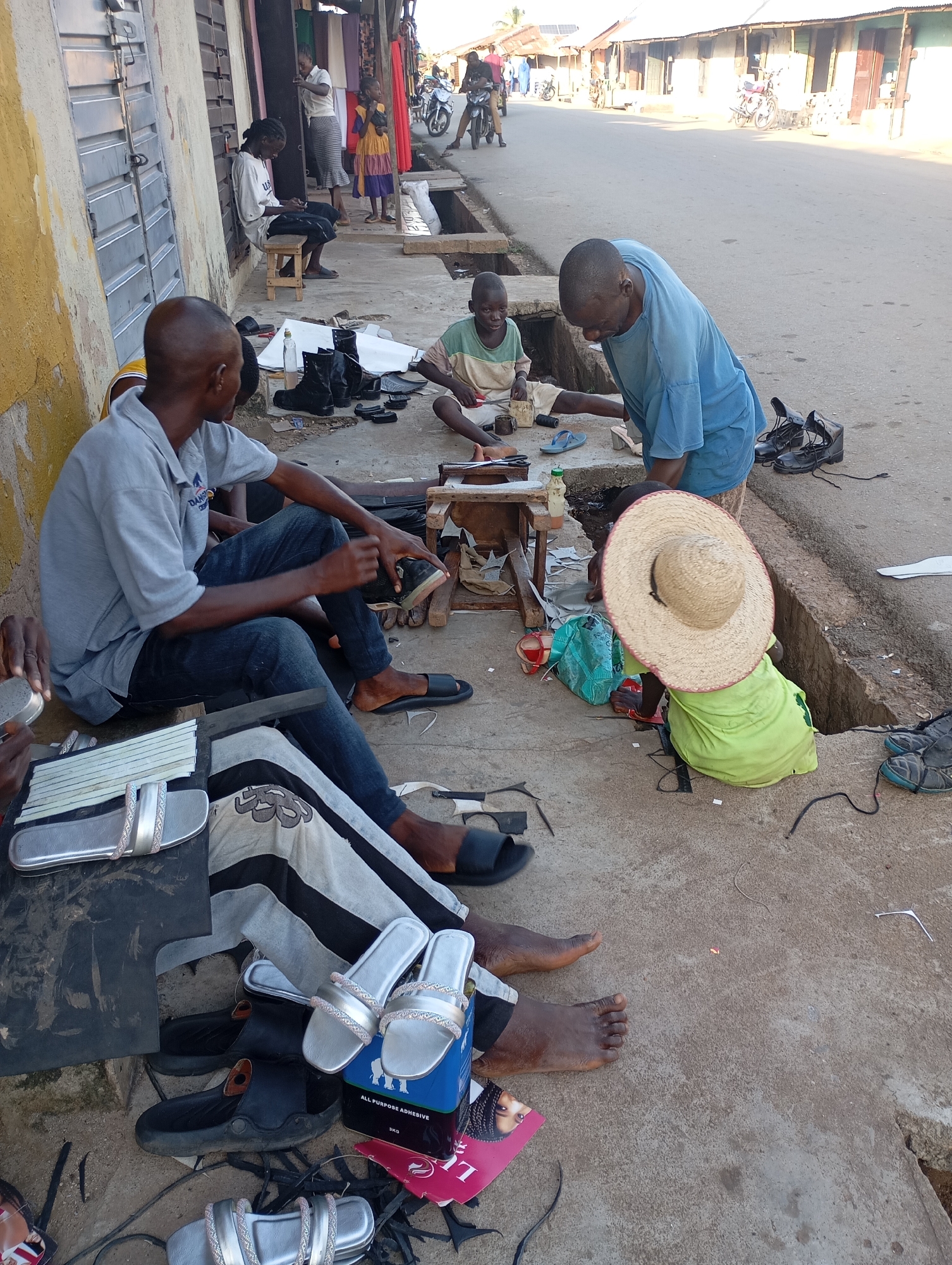 Sidewalk cobblers craft and repair sandals on a Shendam street