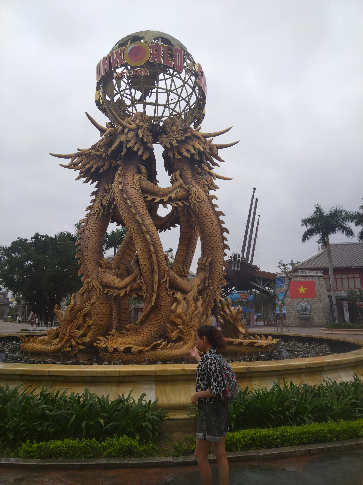 Tourist visits golden dragon monument, poses for photos