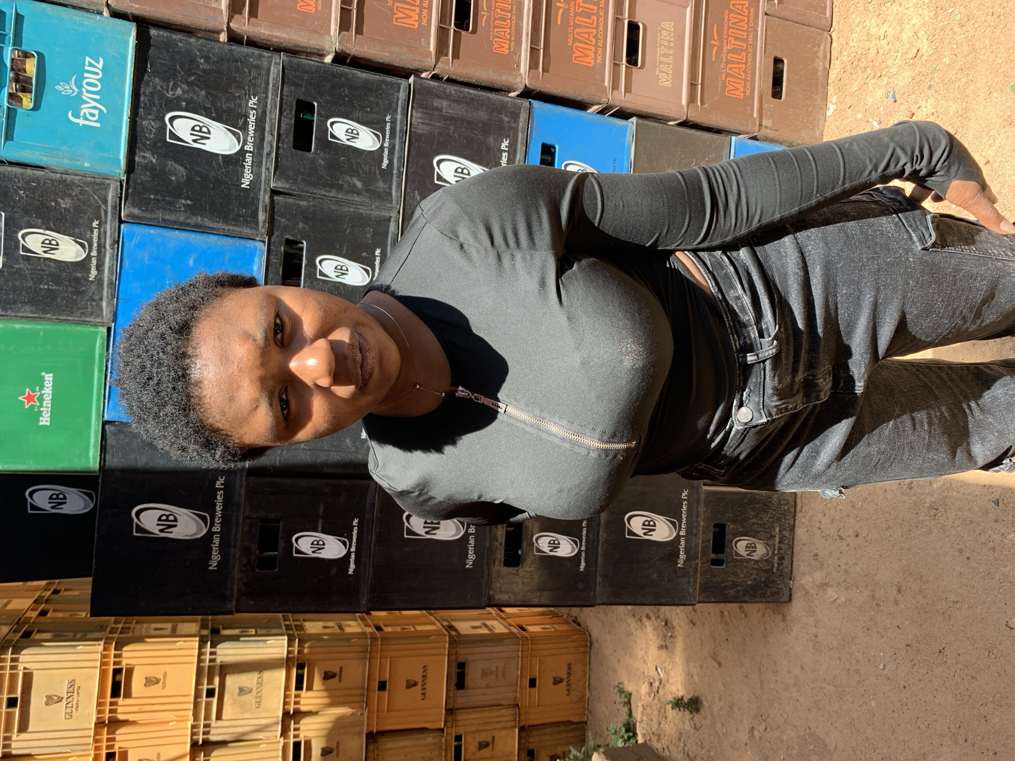 Woman poses among brewery crates in Gura Top Nigeria