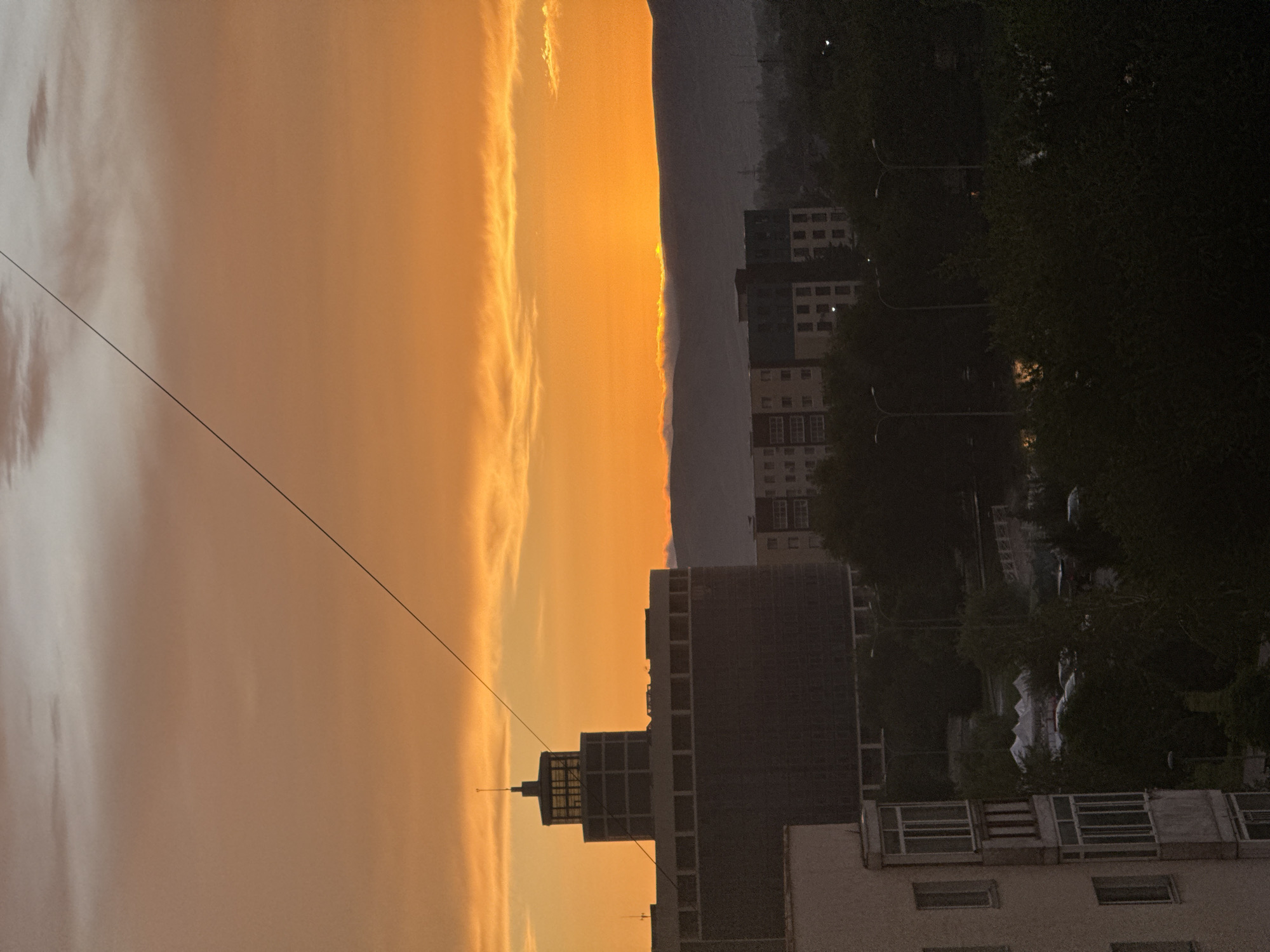 City skyline glows orange and yellow at sunset.