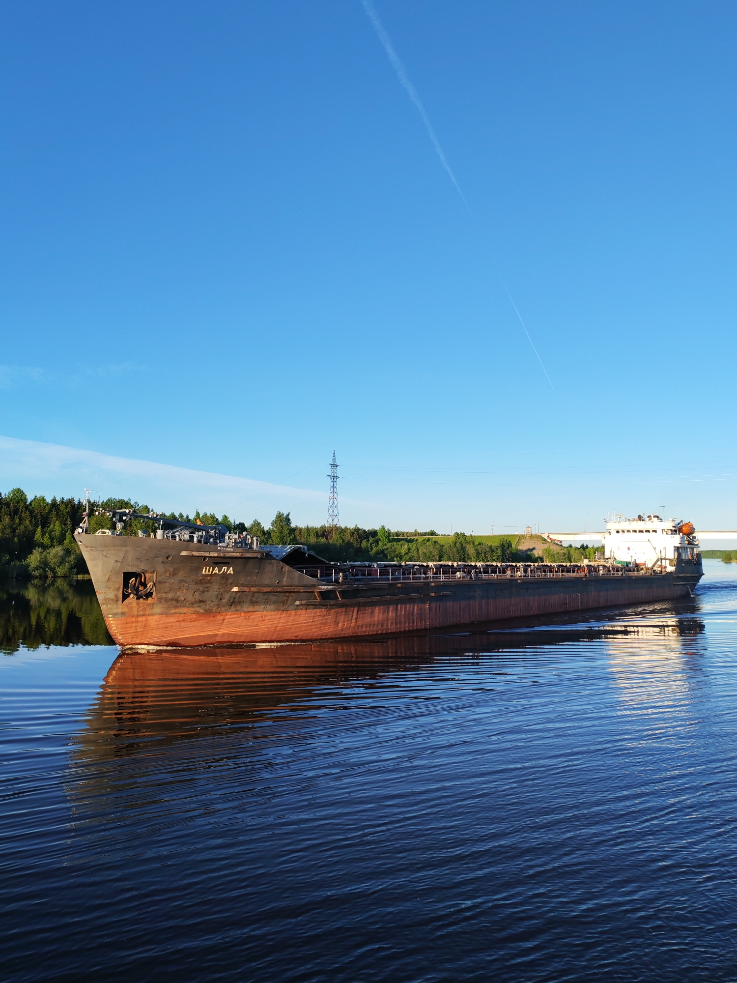 Cargo ships navigate Sheksna River under clear skies