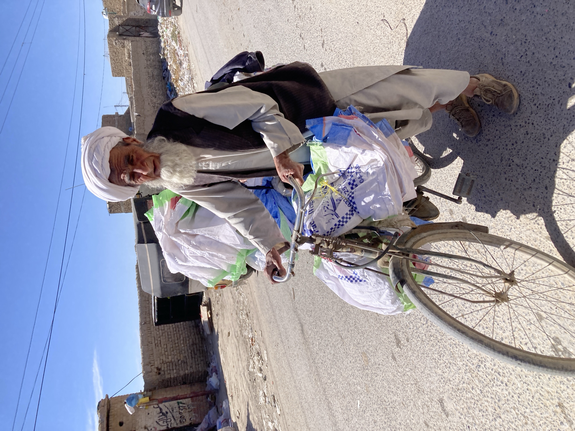 Elderly man cycles through Quetta streets in traditional dress
