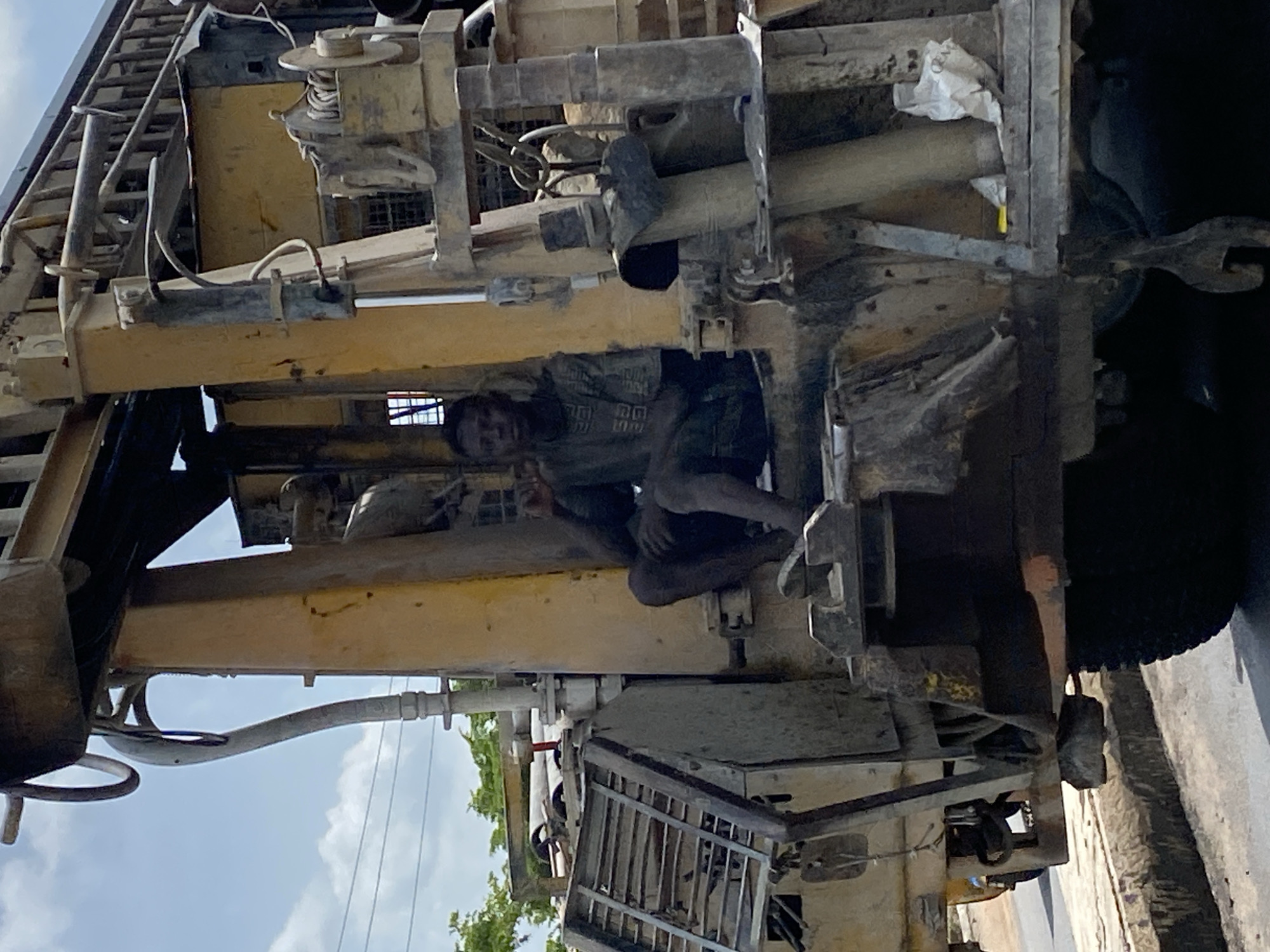 Man sits inside yellow machinery on Lokoja road