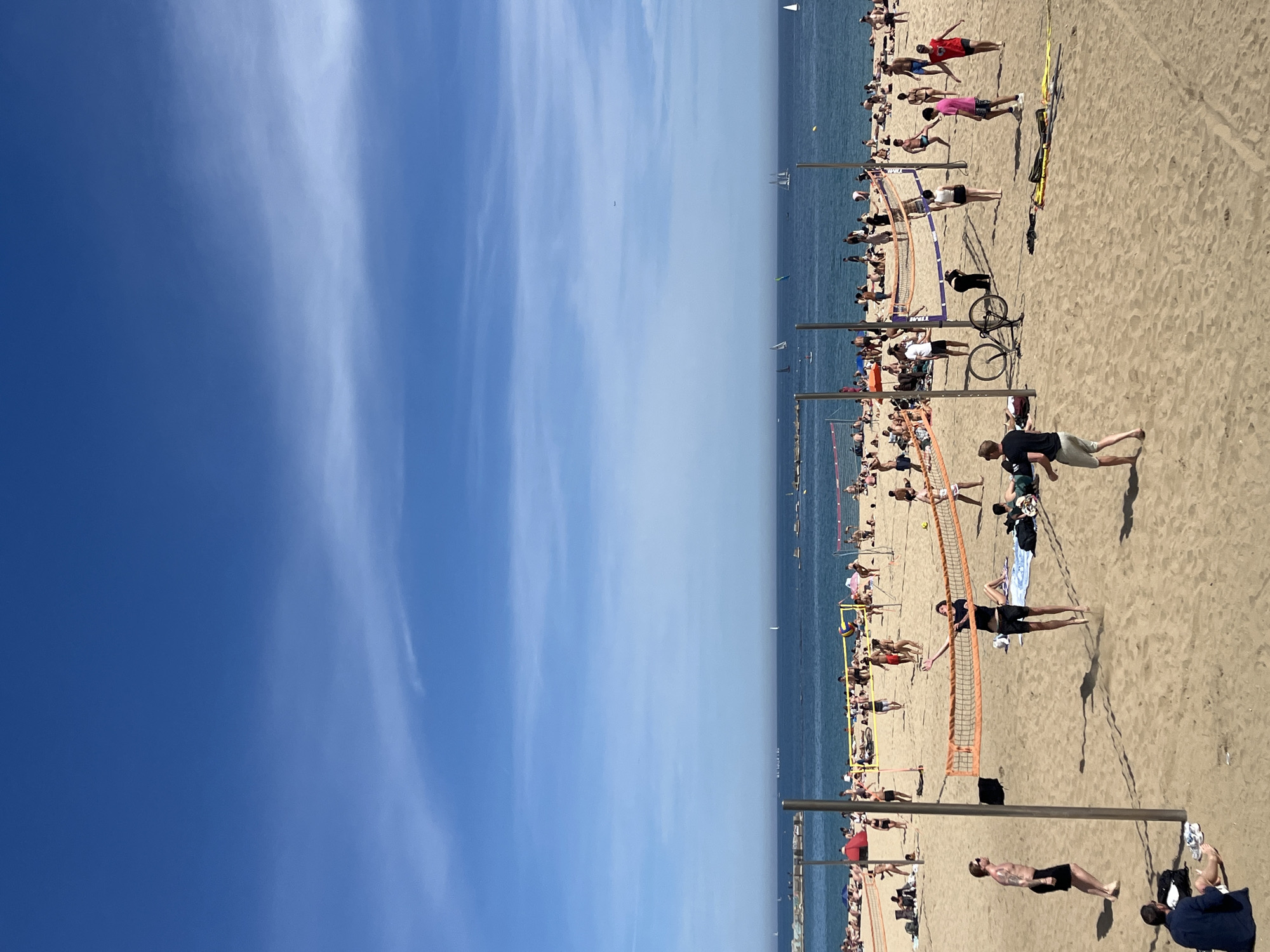 Busy afternoon observed at Barcelona's Barceloneta Beach under clear skies
