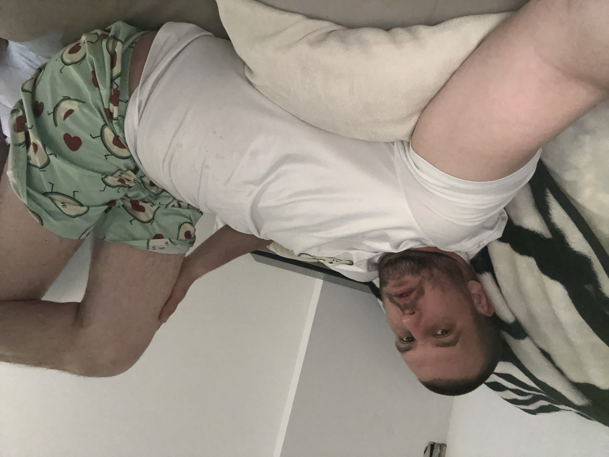 Man rests on bed in avocado shorts, Sofia