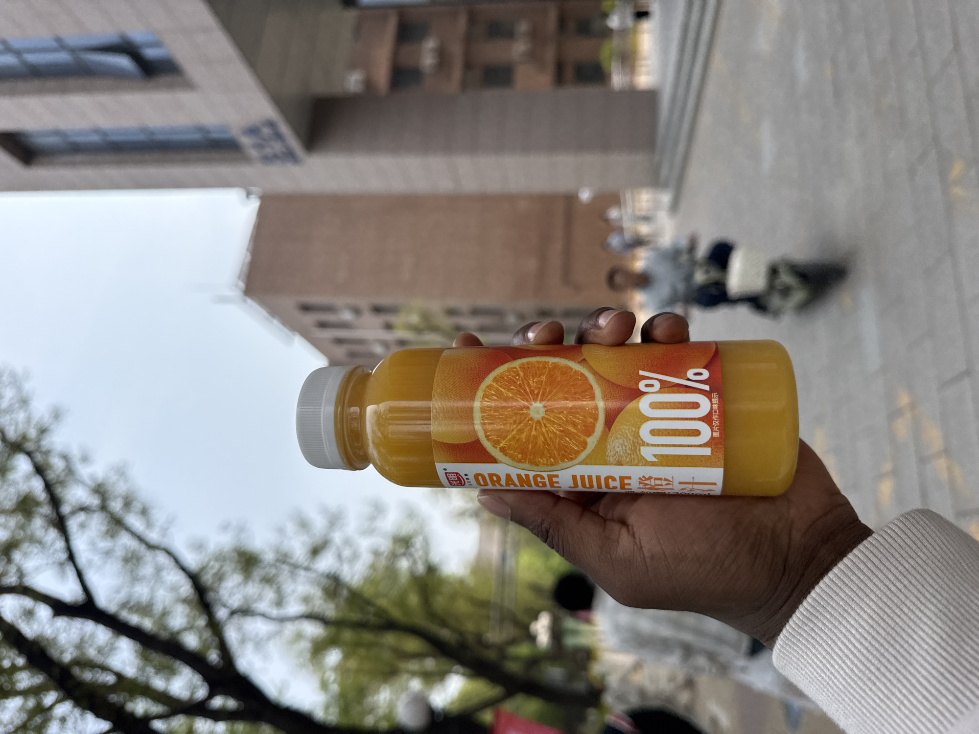 Orange juice bottle displayed against Beijing cityscape
