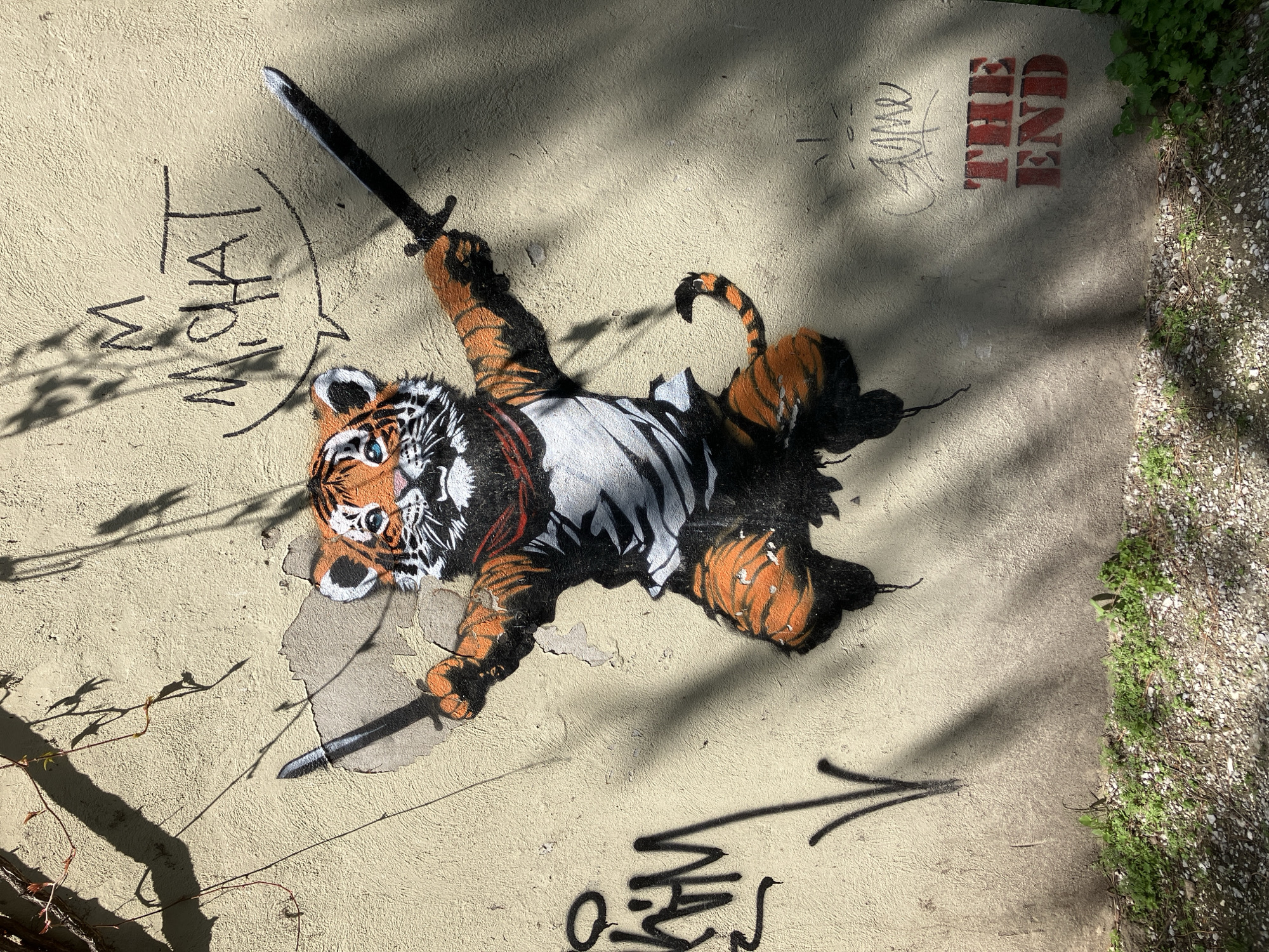 Street mural shows tiger with swords on concrete wall