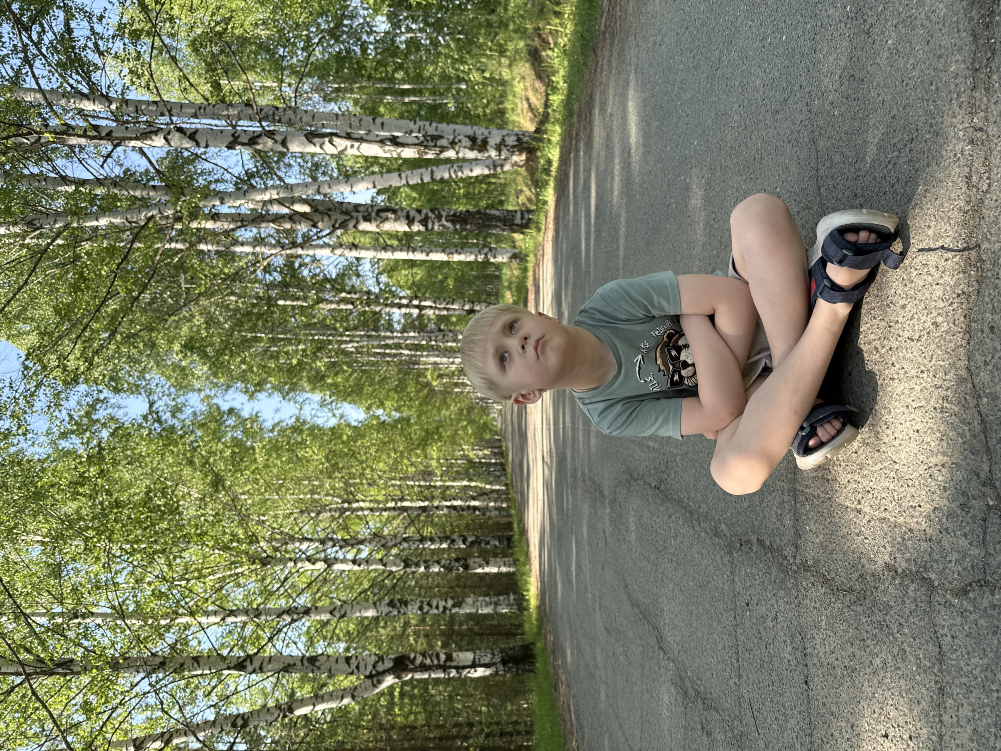 Boy sits on rural road in Банное, Russia