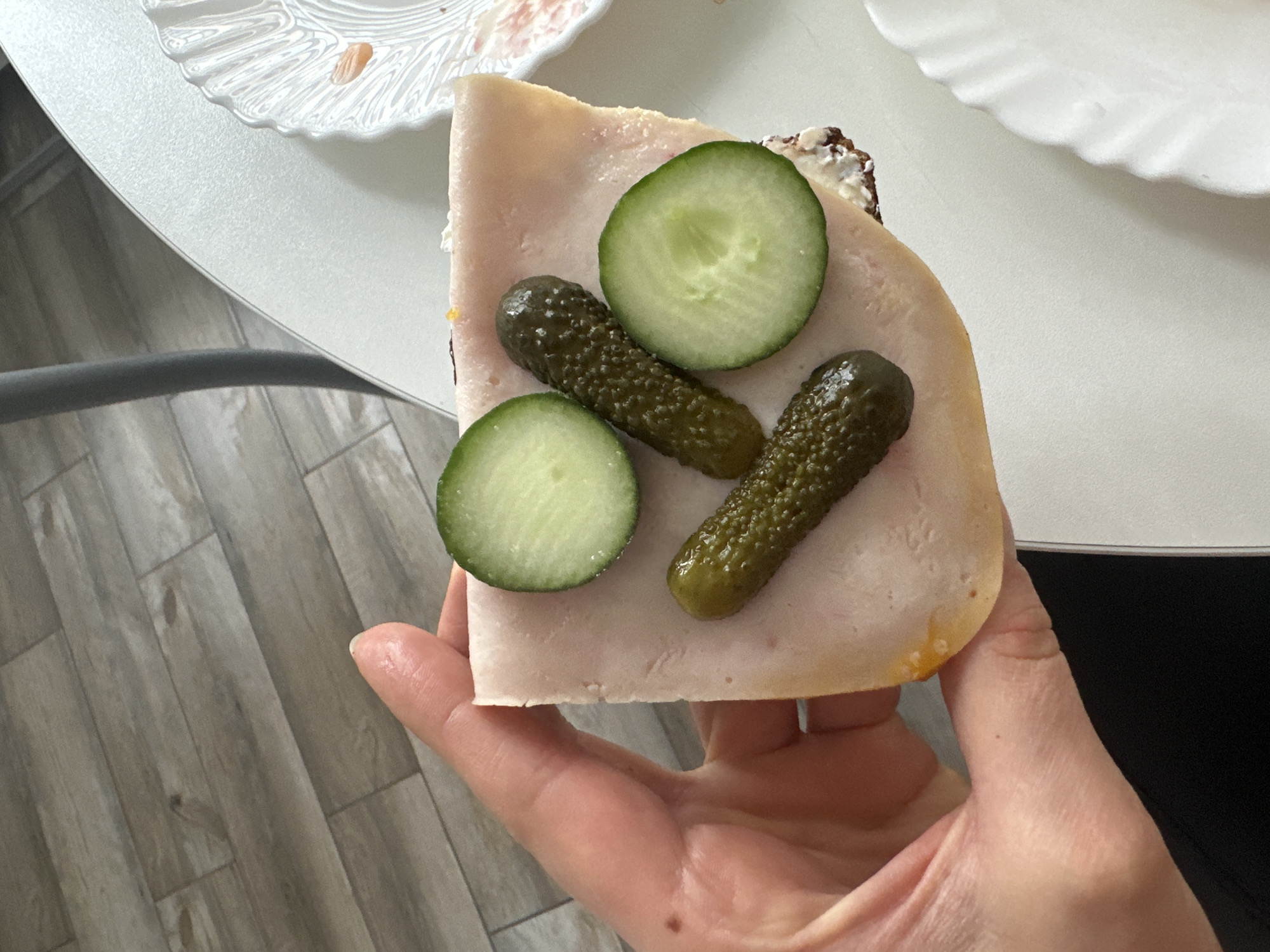 Person holds deli sandwich with pickles in Sochi