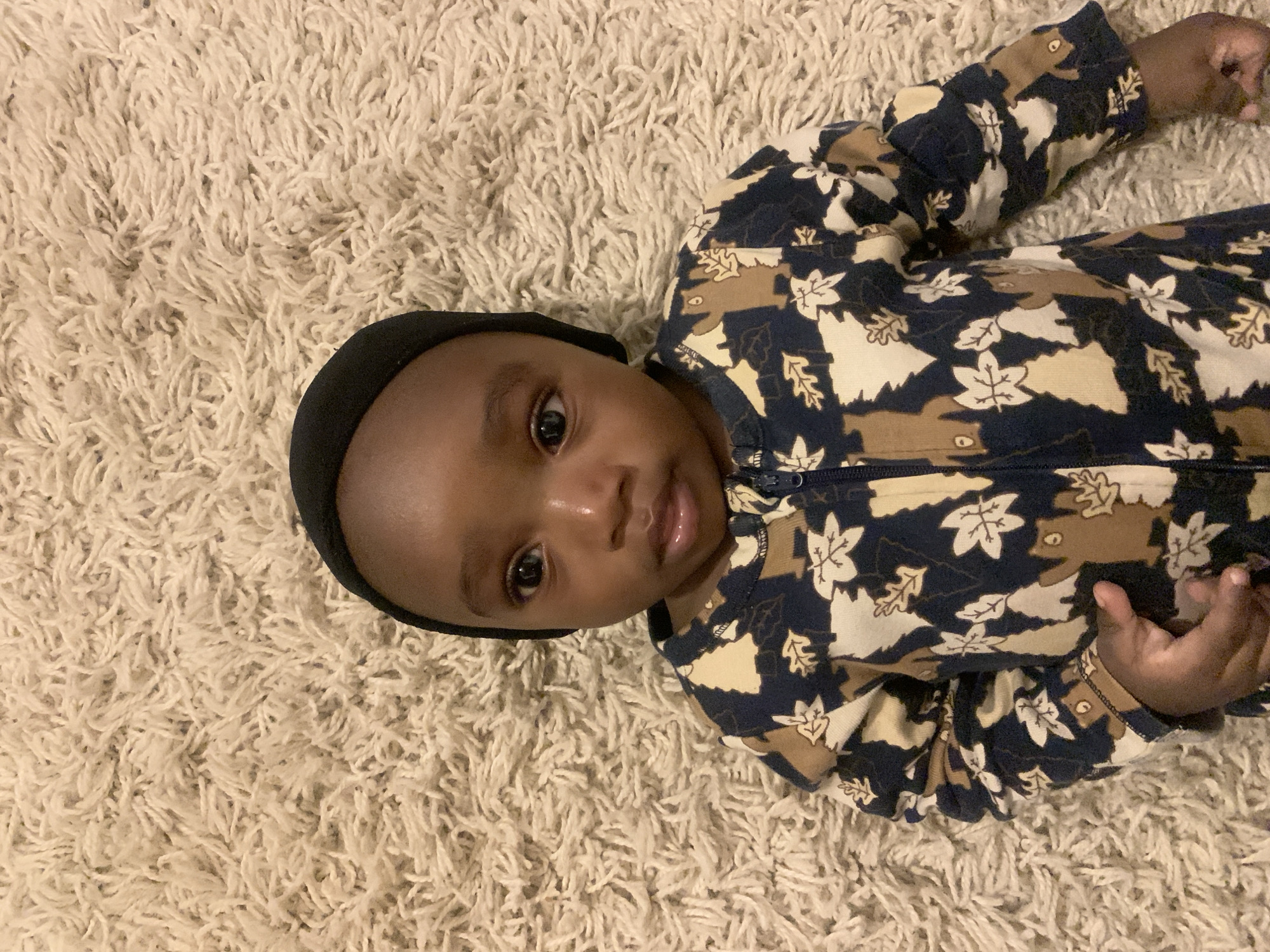 Baby in patterned outfit photographed on rug in Nigeria